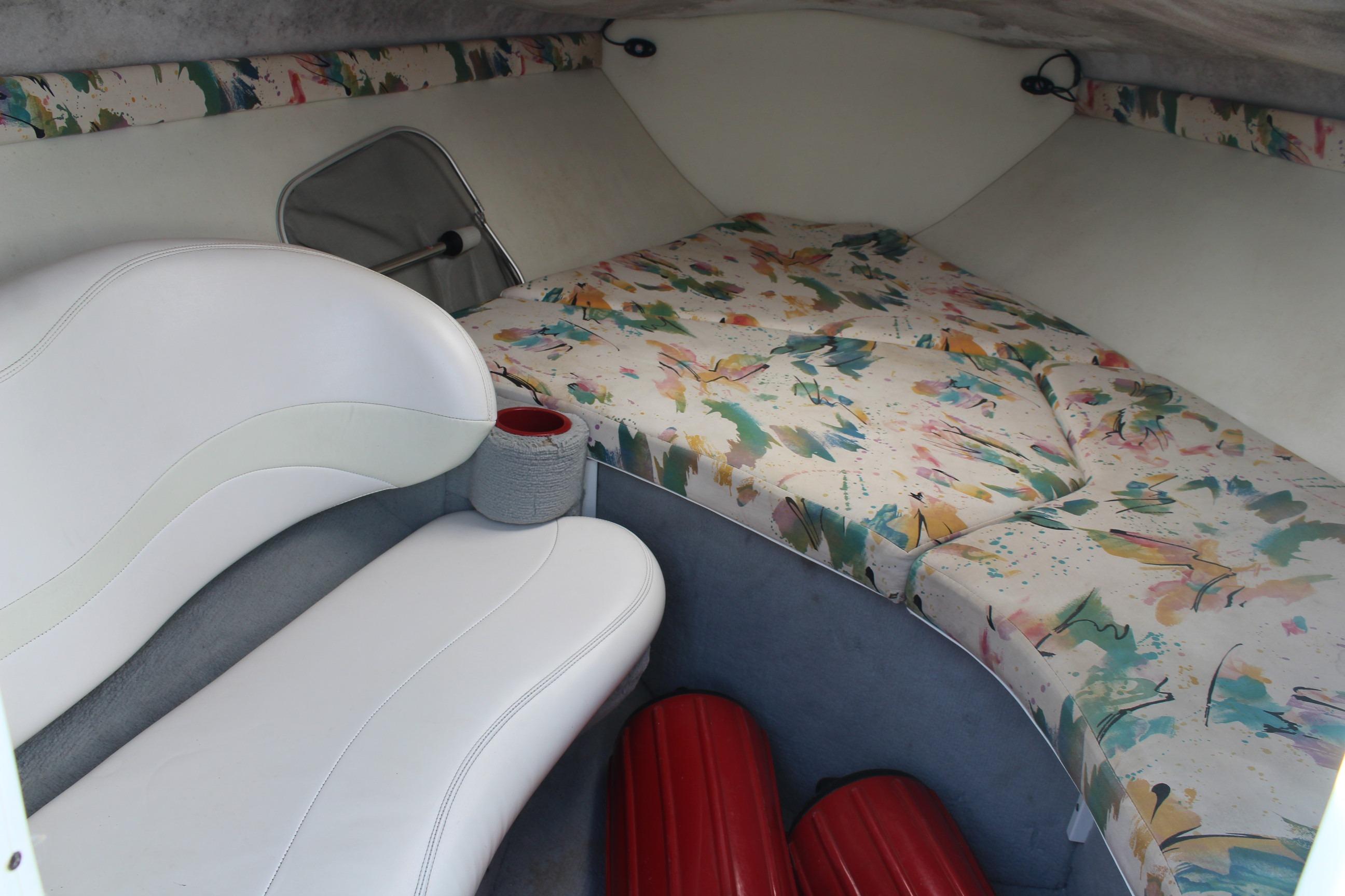 Interior of 1996 Baja 232 boat with colorful bedding and white seating.