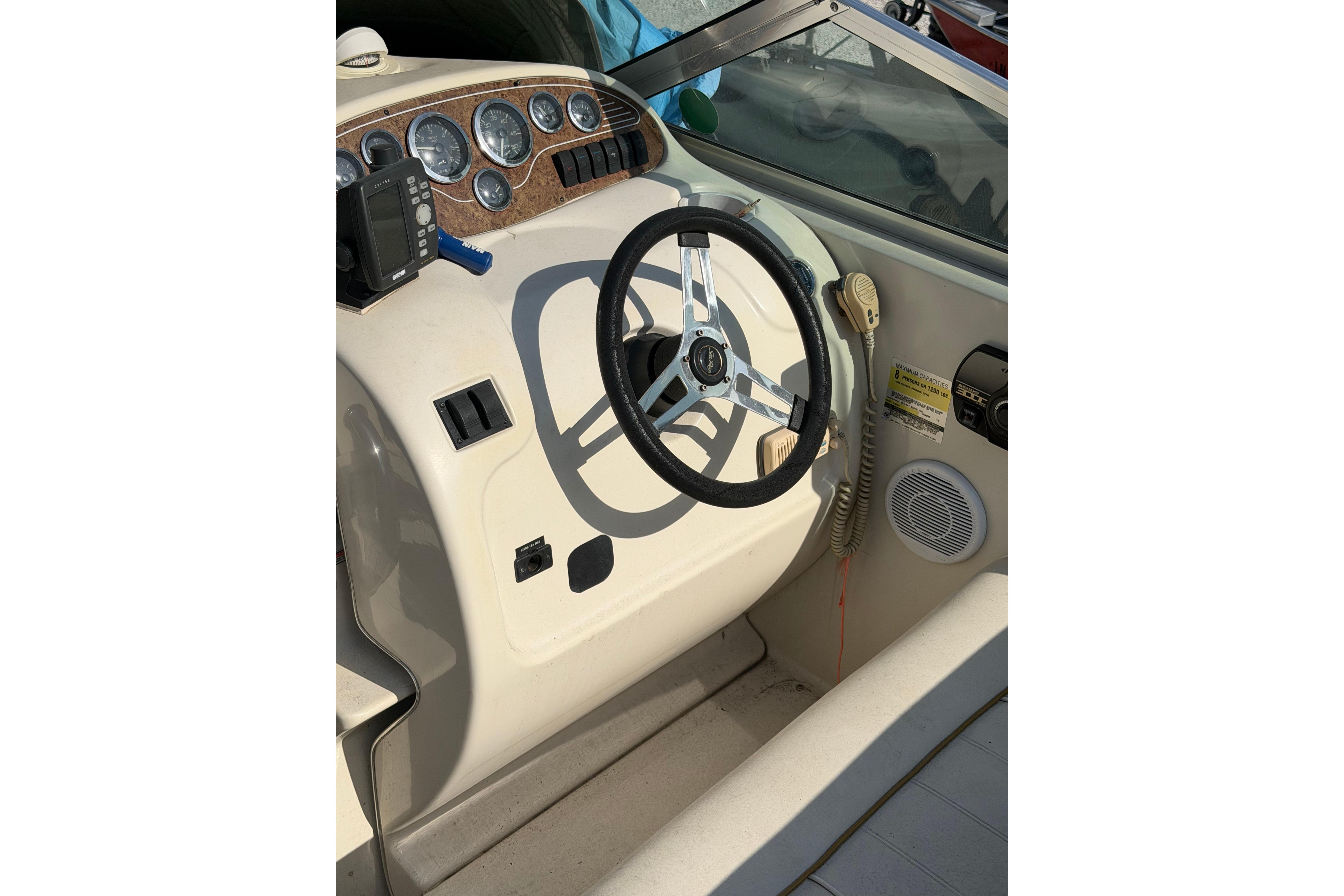 Steering console of a 1999 Sea Ray 240 Sundancer boat with gauges and controls.