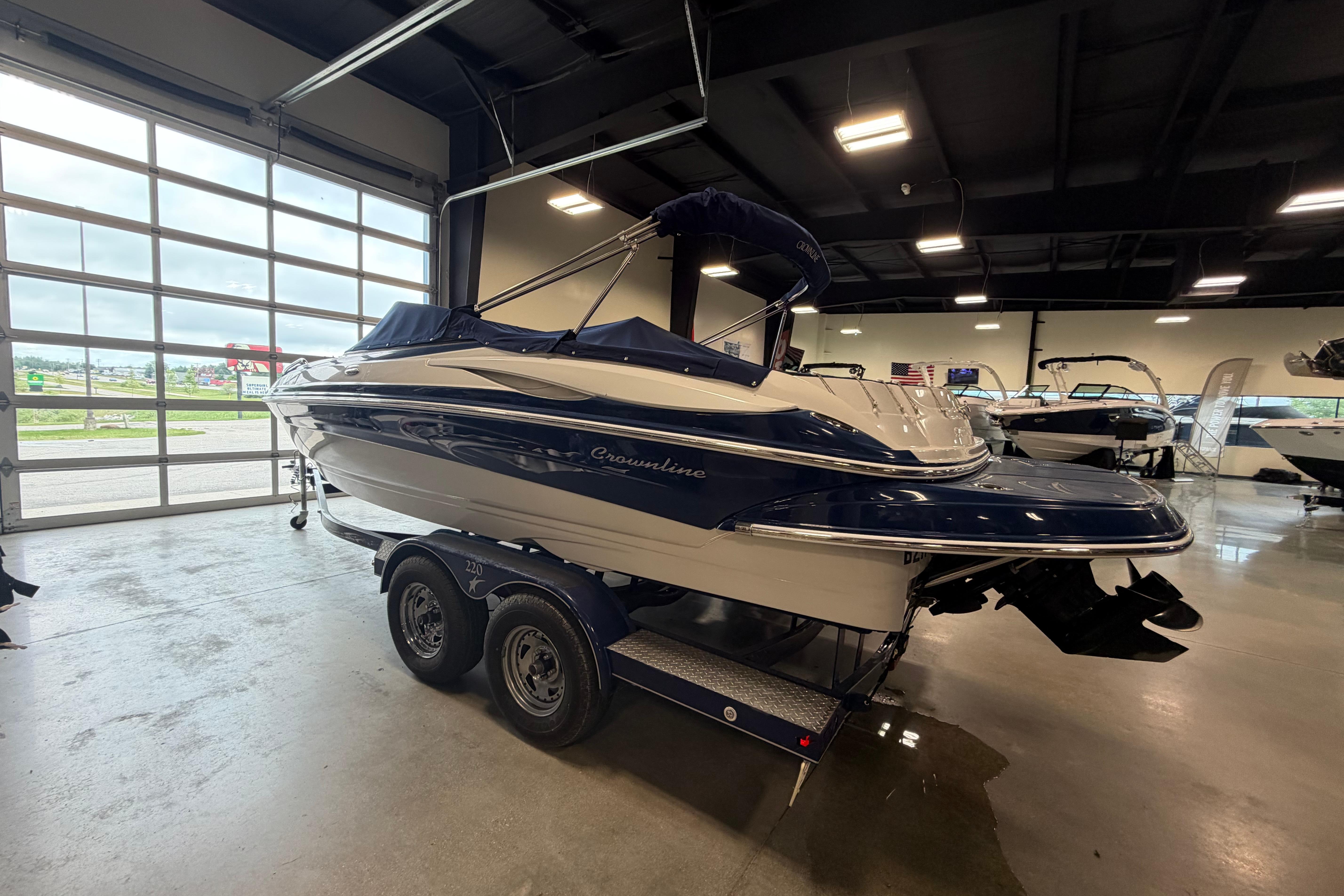 2008 Crownline 220 LS boat in showroom, featuring sleek design and dual-axle trailer.