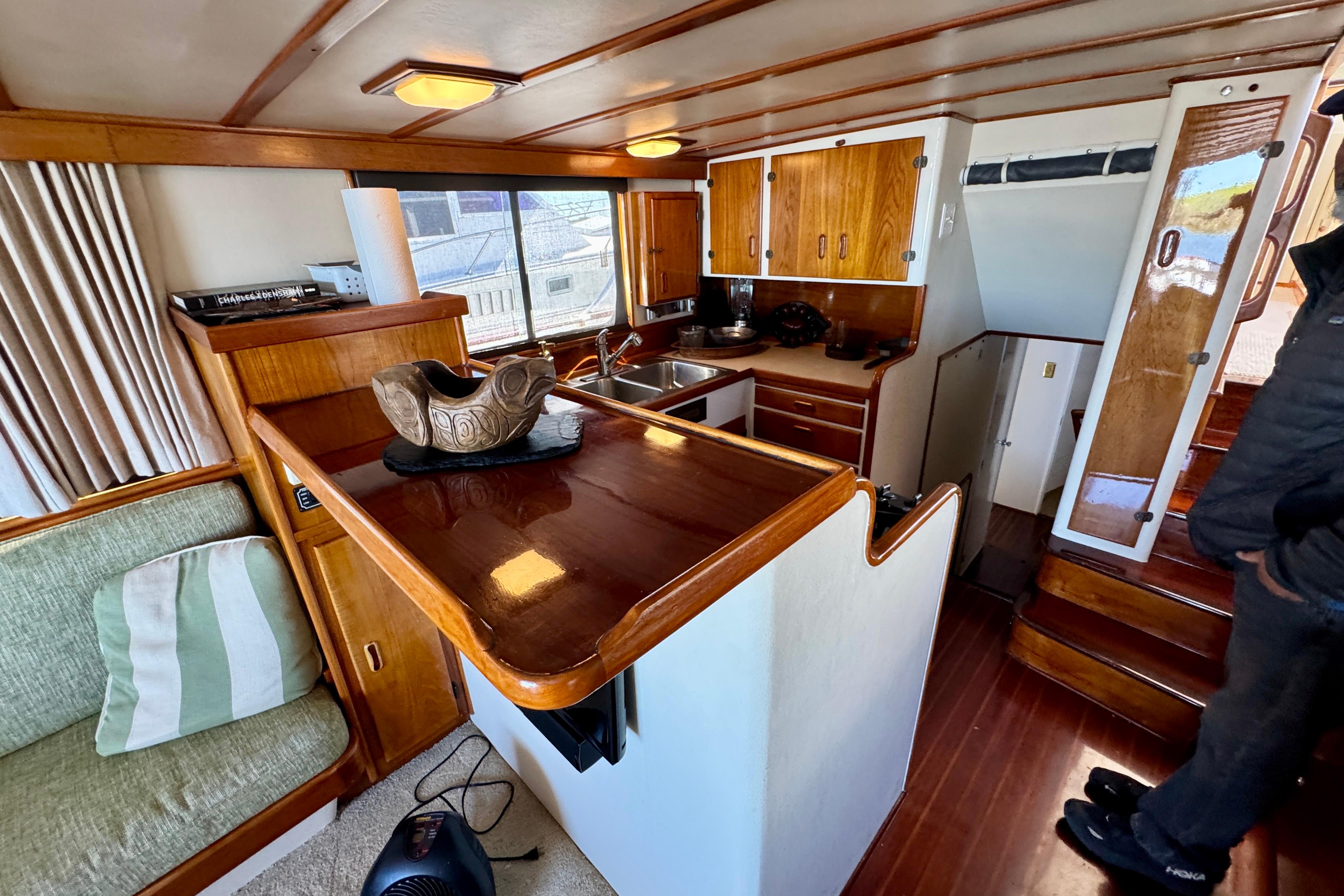 1958 Blanchard Pilothouse interior with wooden cabinetry, cozy seating, and nautical decor.