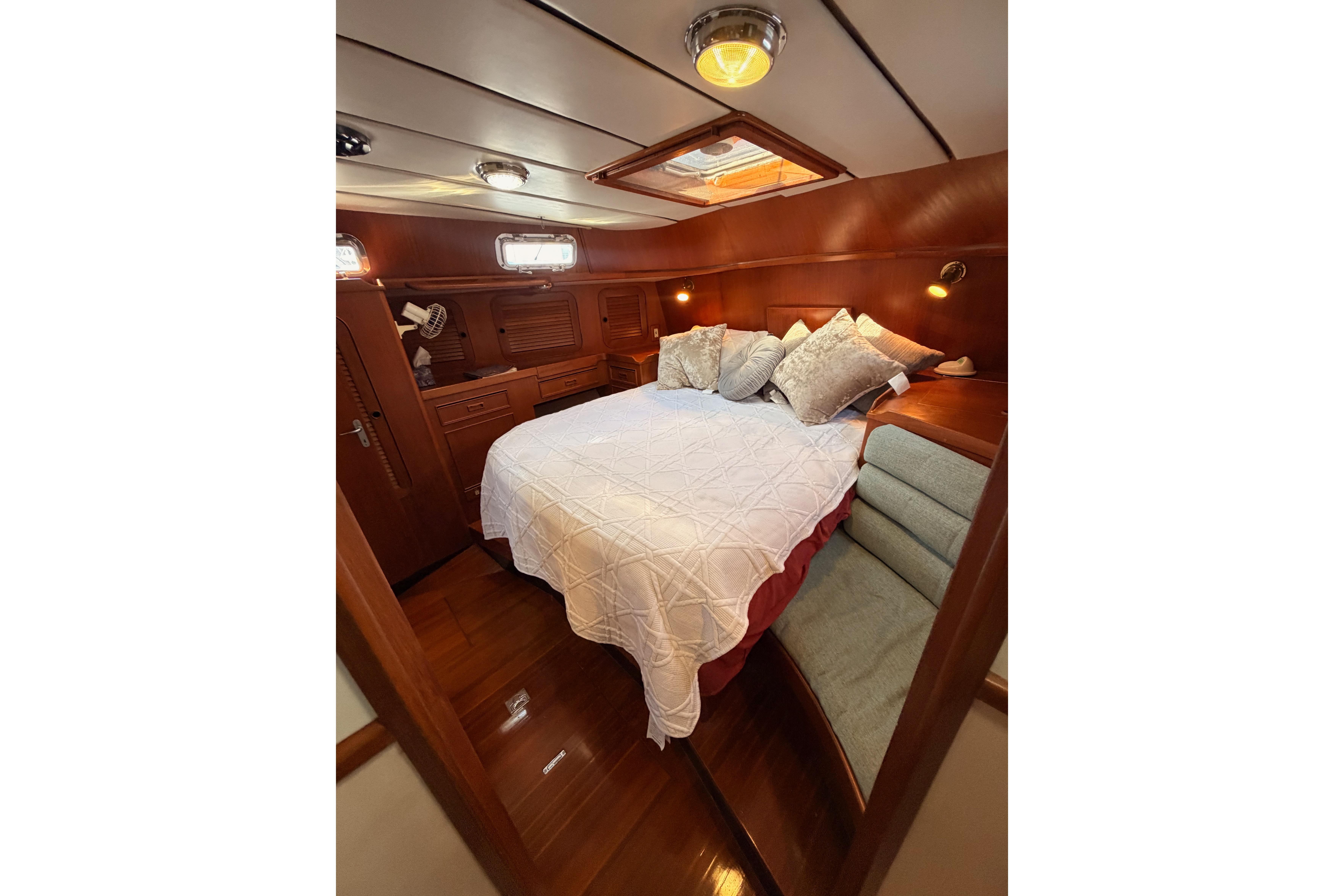 Luxurious cabin interior of a 1991 Hylas 51 yacht with cozy bedding and wood finish.