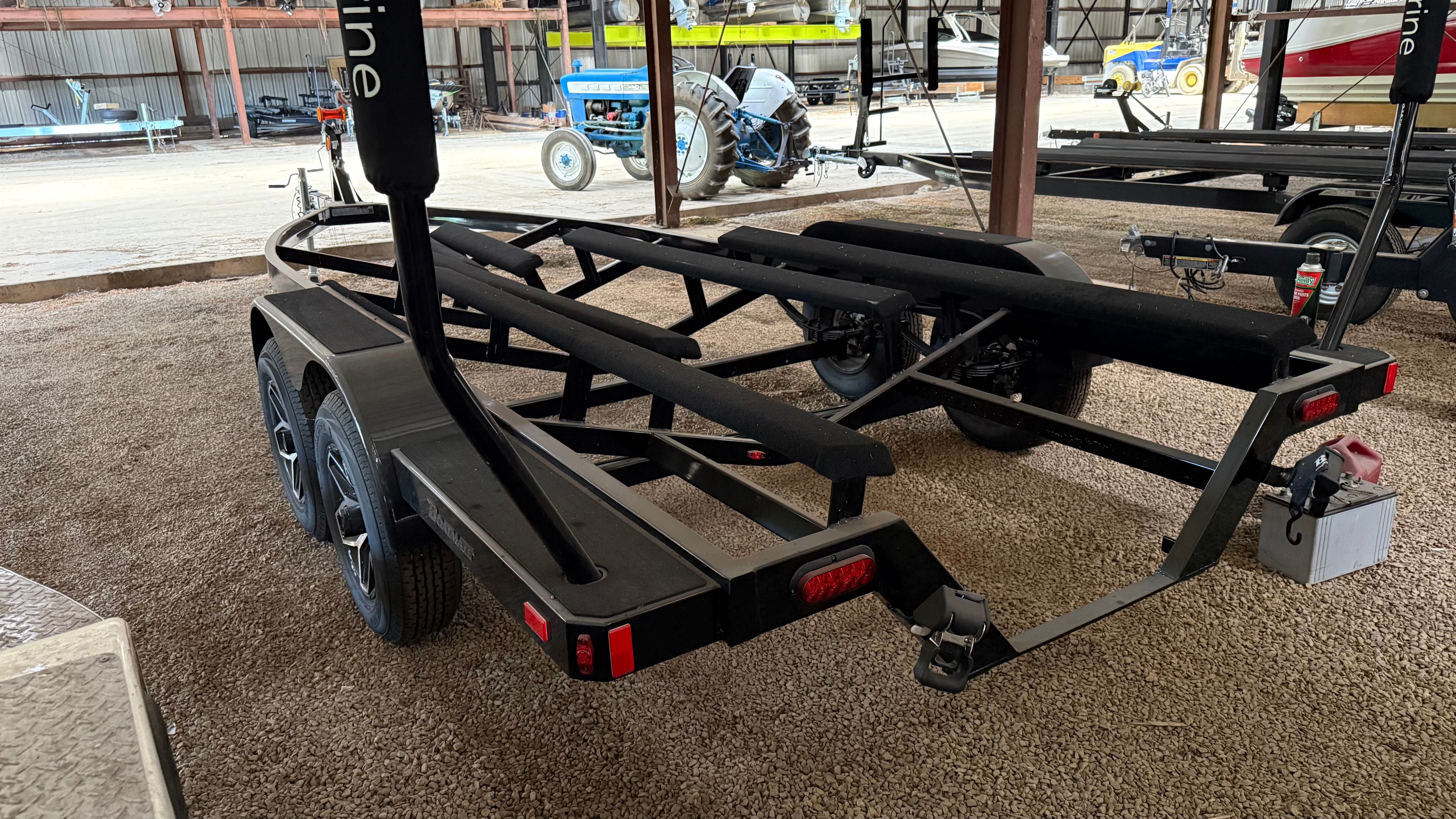 A boat trailer sits on gravel in a covered area.