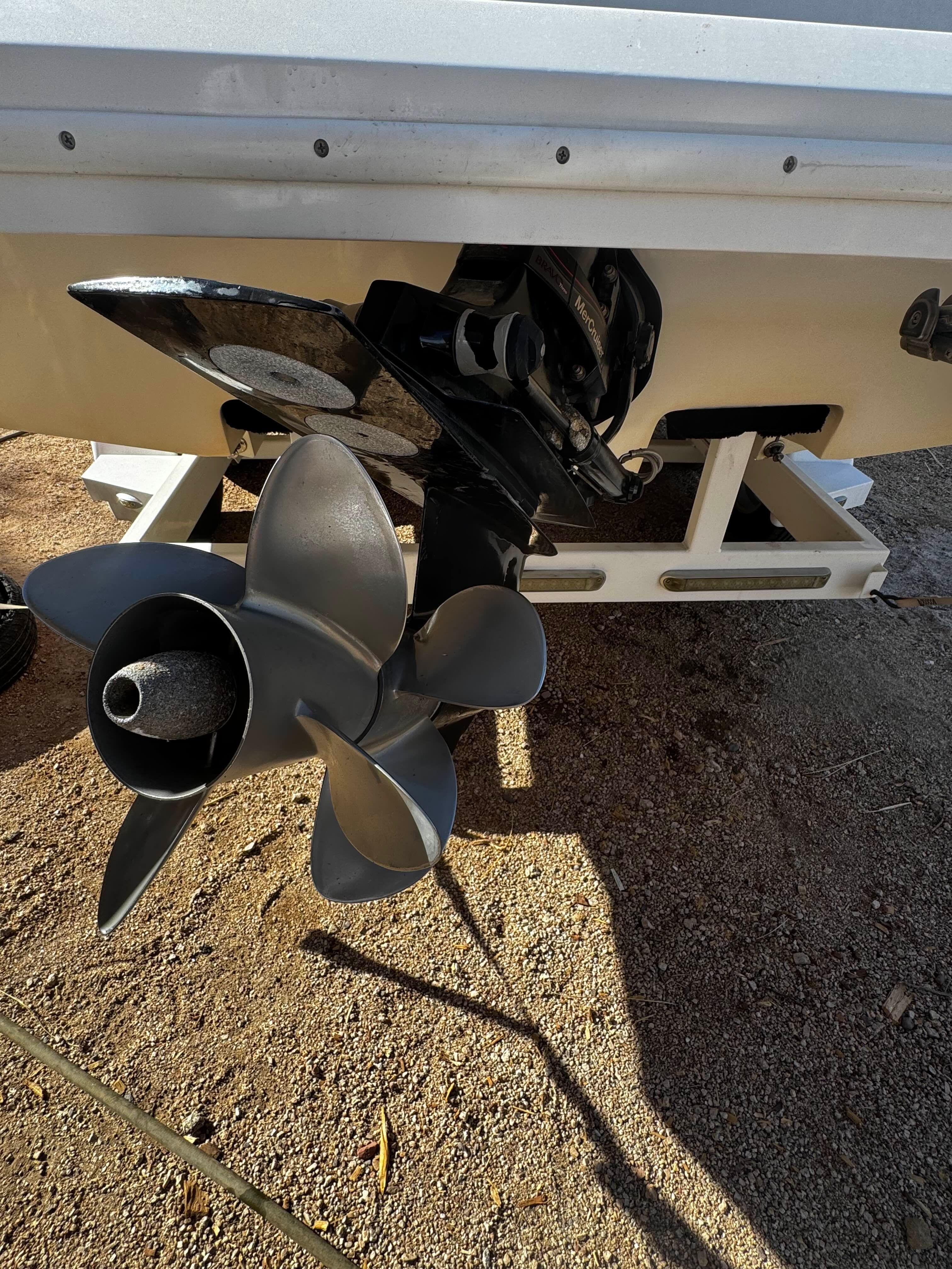 Close-up of a boat propeller on dry ground.