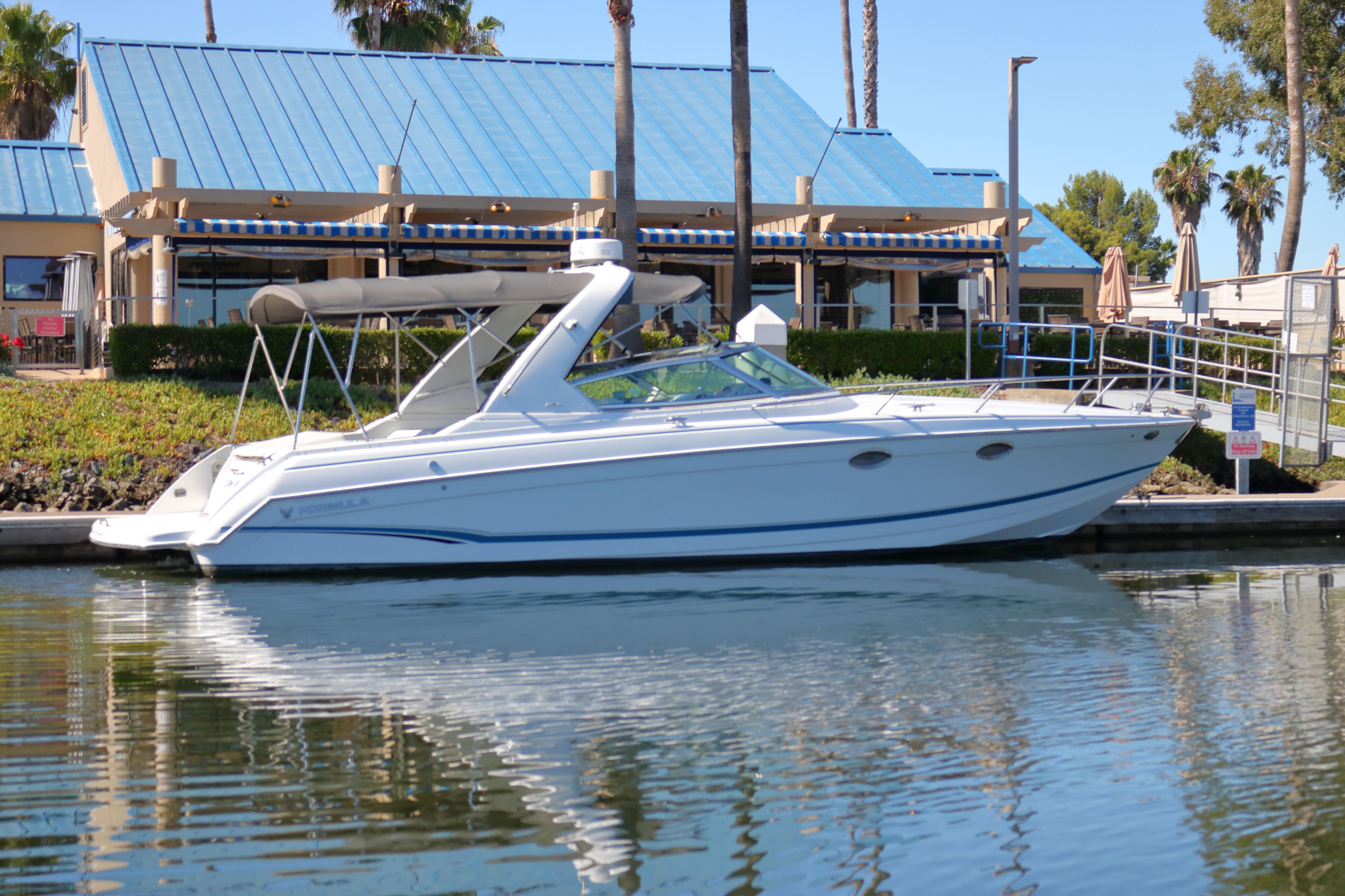 2006 Formula 330 Sun Sport boat docked near waterfront building.