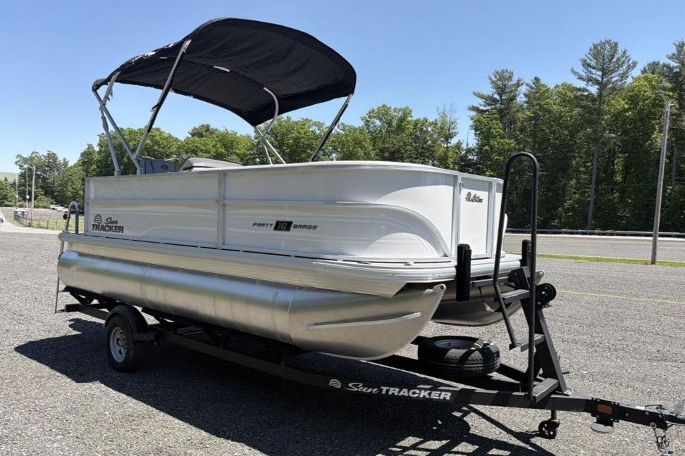 2026 Sun Tracker Party Barge 18 DLX pontoon boat on trailer, parked outdoors.