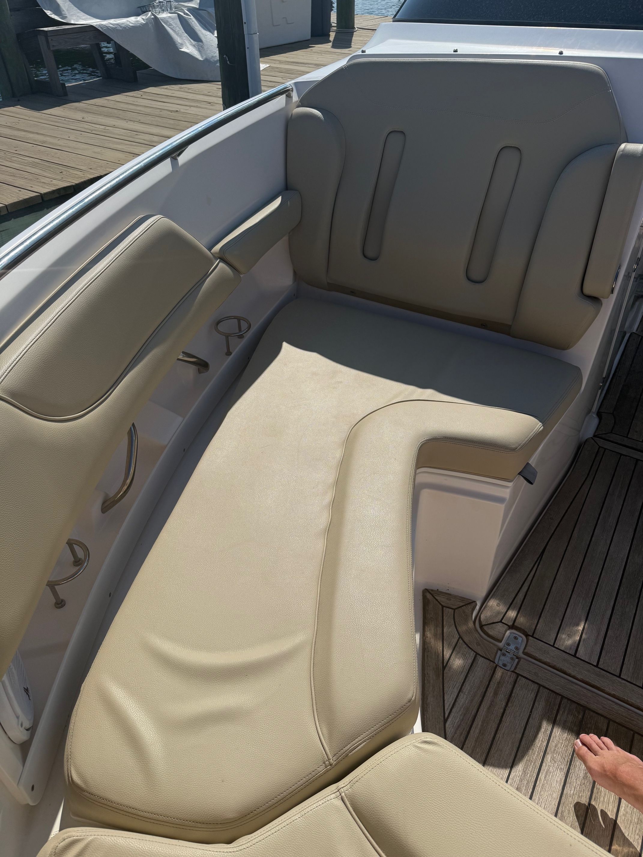 The image shows a beige upholstered seating area on a boat with a wooden floor.