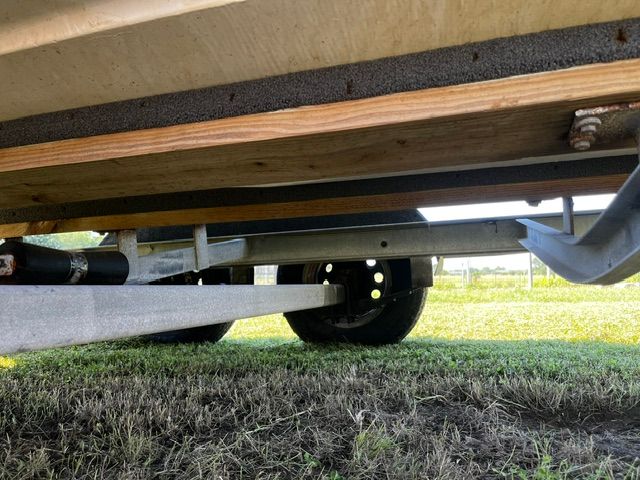 A boat on a trailer is parked on grass.