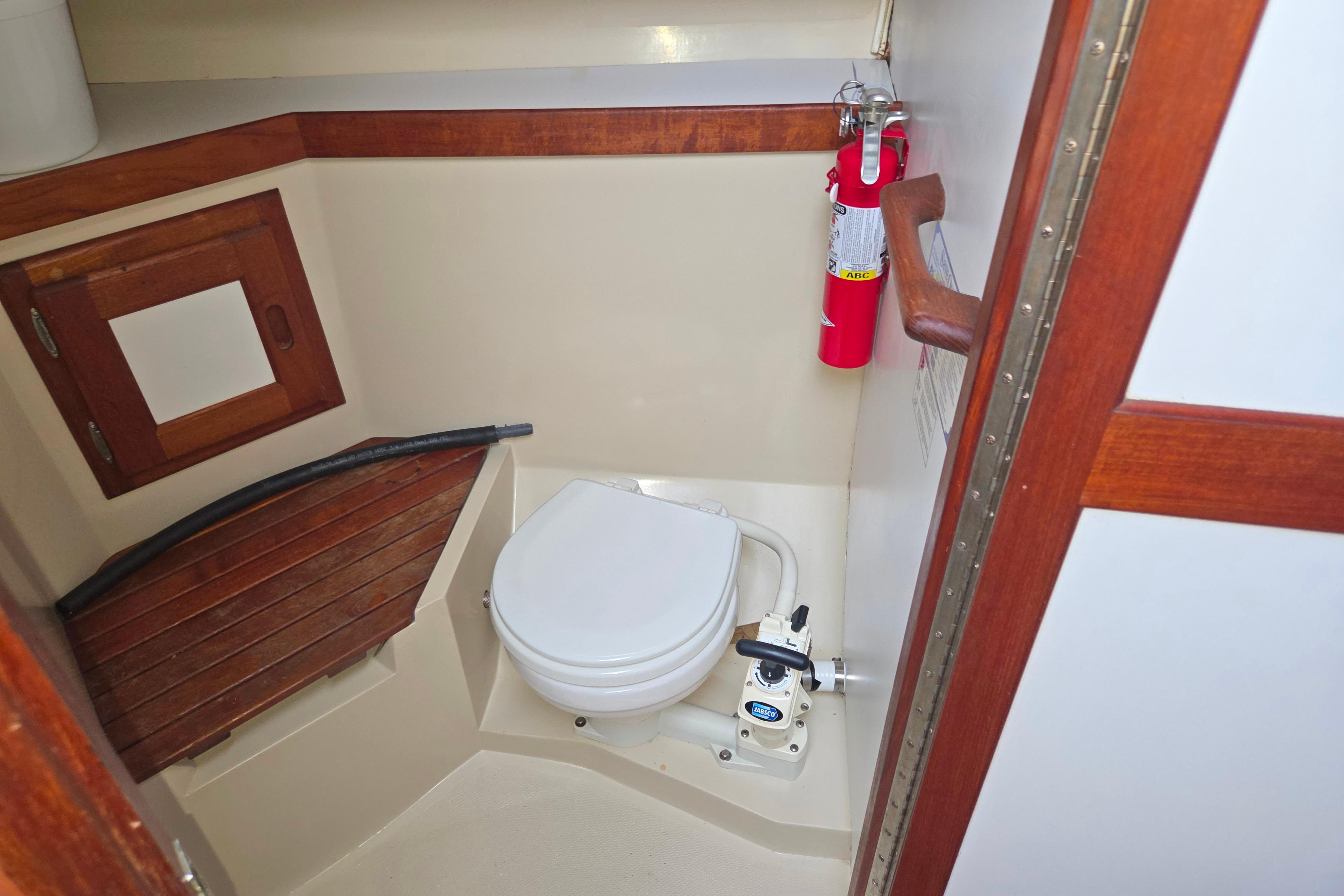 1986 Catalina 355 boat bathroom with toilet, wooden accents, and fire extinguisher.
