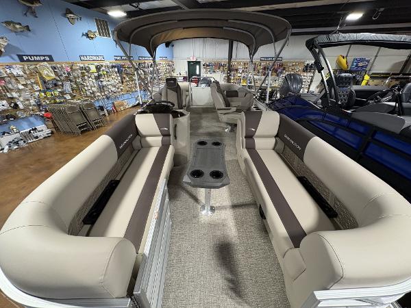 2025 Bennington 23 SSR pontoon boat interior with beige seating and canopy in showroom.