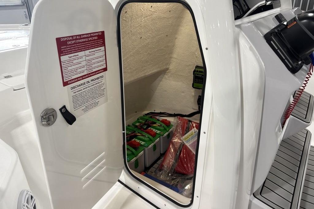 2026 Tidewater 2210 Carolina Bay storage compartment with safety equipment and disposal instructions.