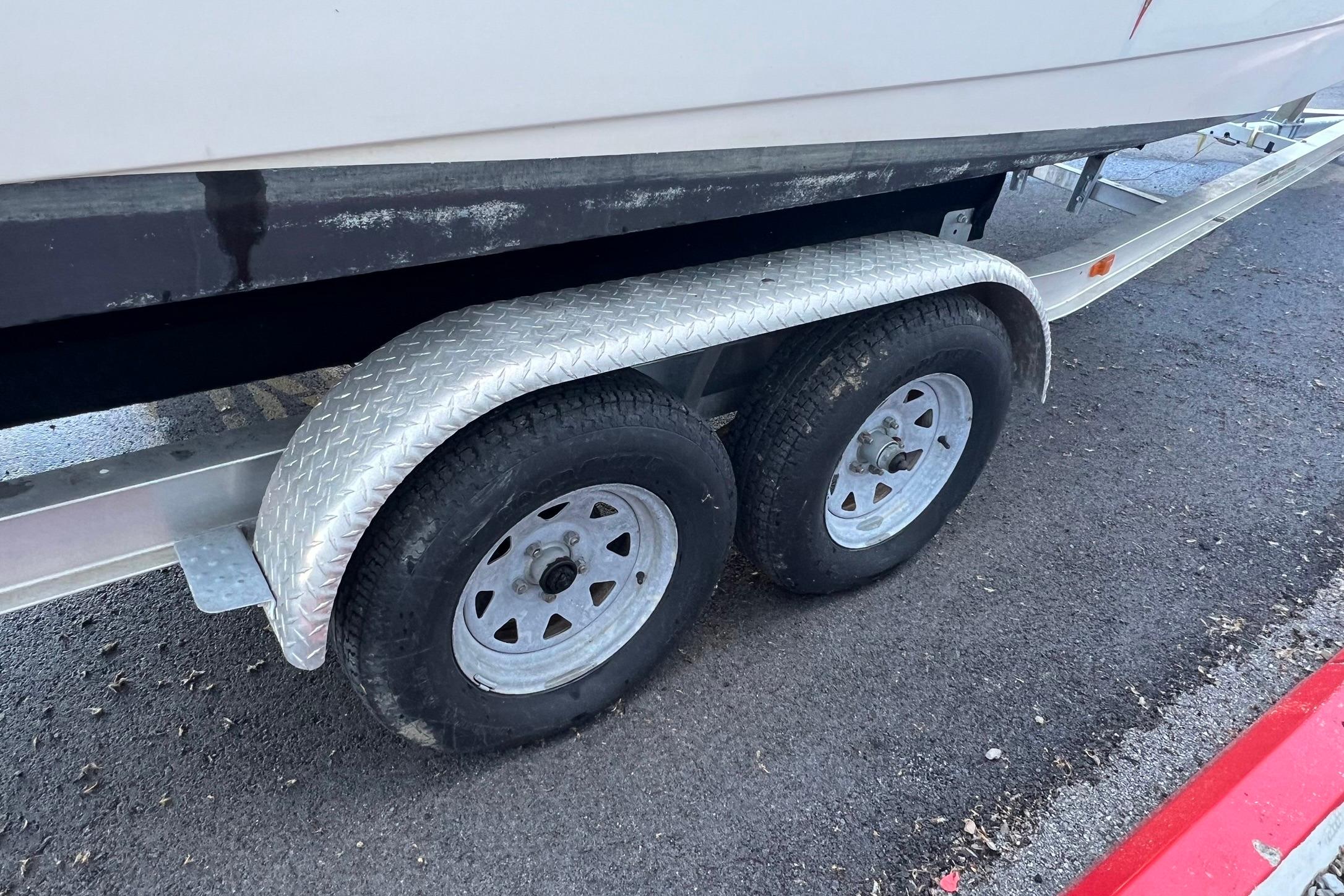 Trailer wheels of a 2006 Edgewater 245CC boat on asphalt pavement.