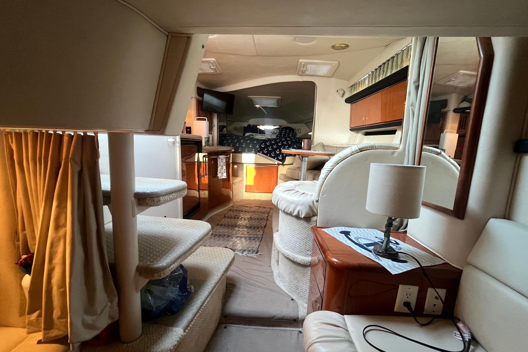 Interior of 2001 Sea Ray 340 Sundancer yacht, featuring cozy seating and elegant wood finishes.