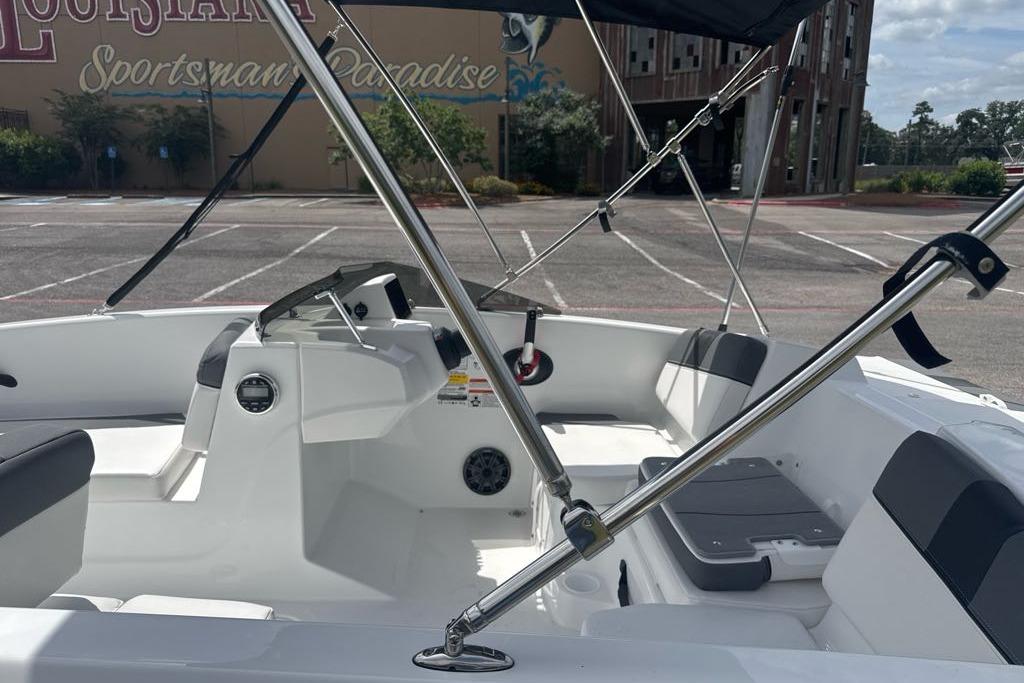 2026 Tahoe T16 boat interior with seating, steering console, and canopy in a parking lot.