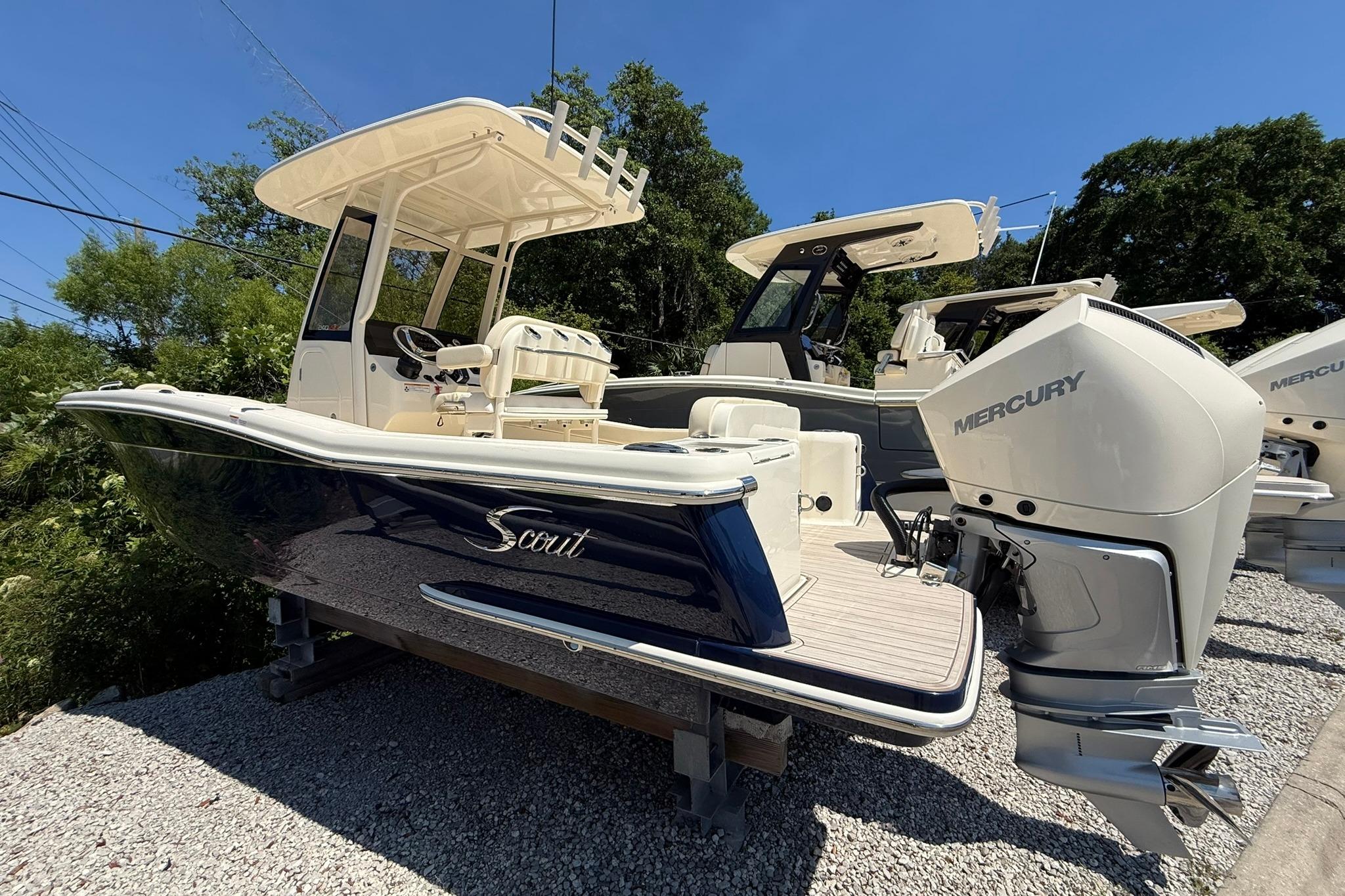 2027 Scout 240 XSF boat with Mercury engine, displayed outdoors on gravel.