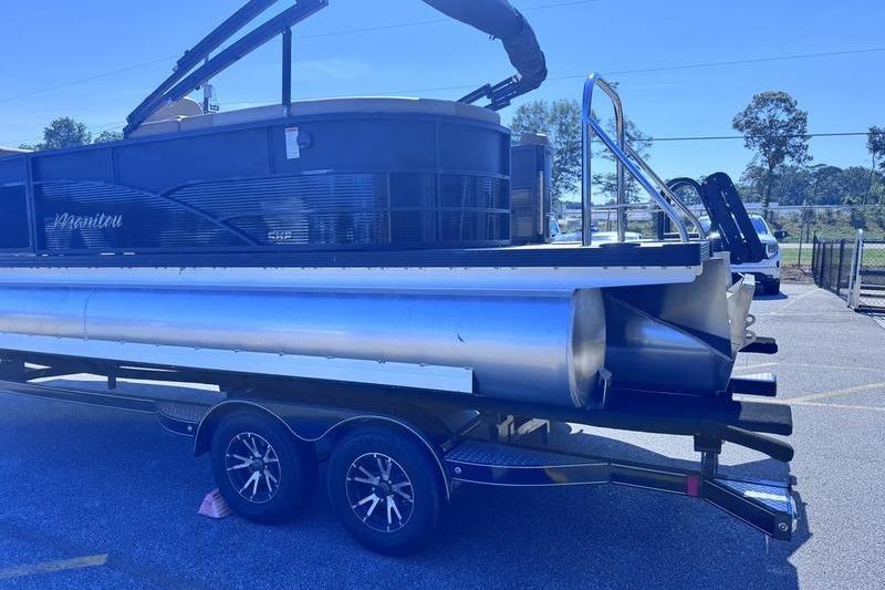 2027 Manitou Aurora 23 RF SHP pontoon boat on trailer, parked outdoors.