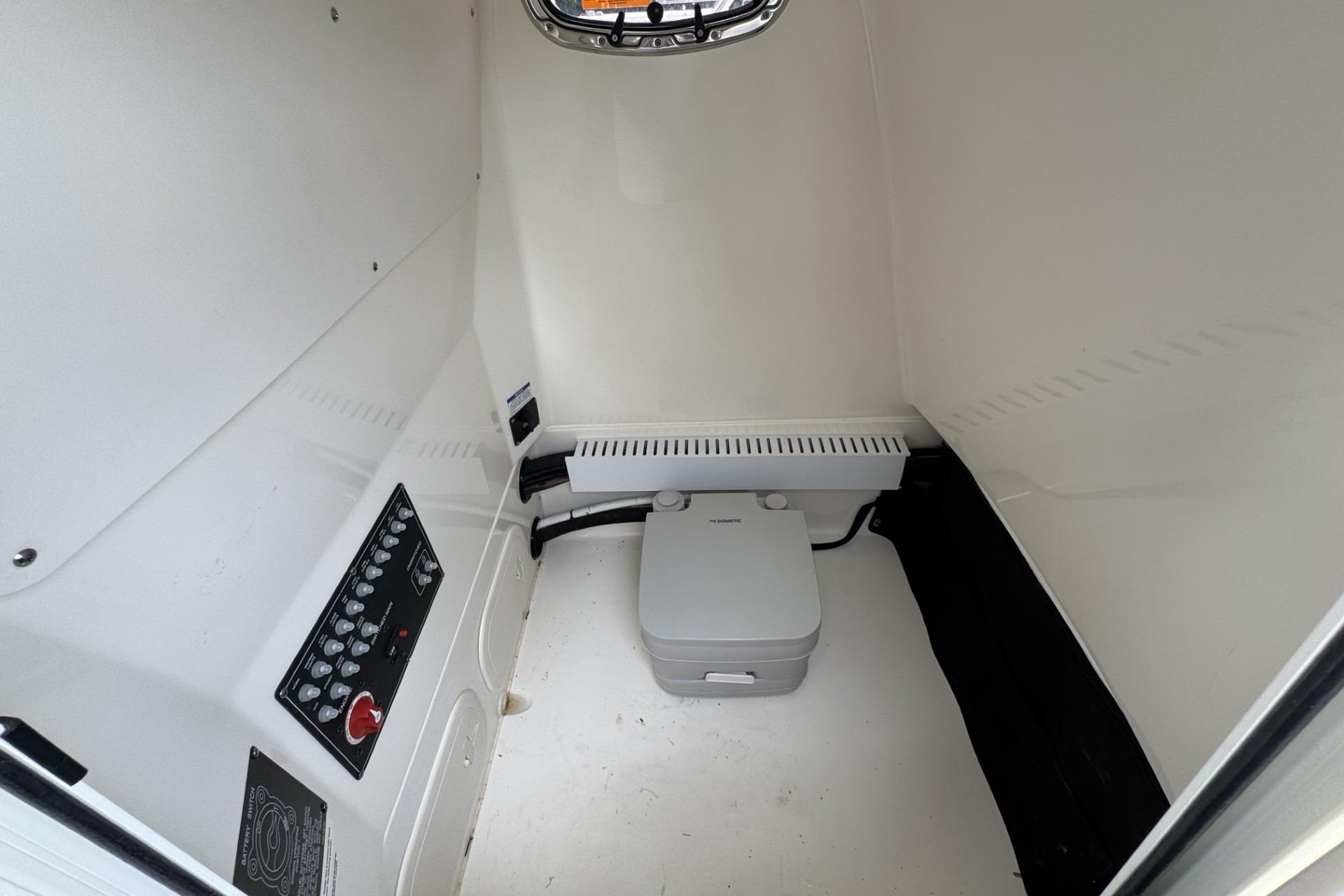 Interior of 2024 Boston Whaler 230 Outrage boat featuring a compact marine toilet.