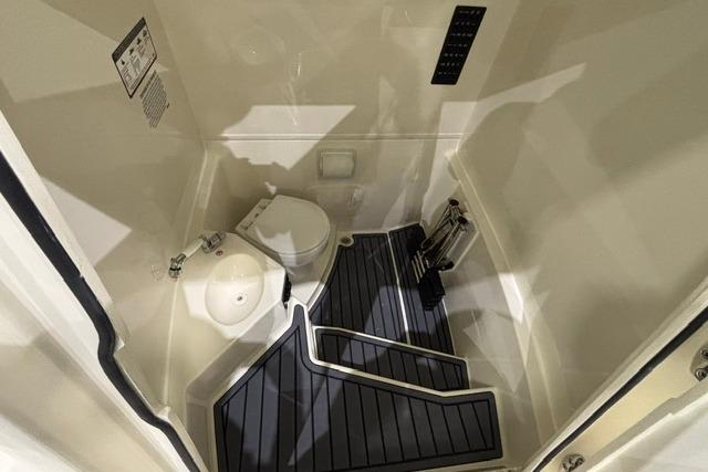 2026 Cobia 245 Center Console boat interior with compact bathroom and modern fixtures.