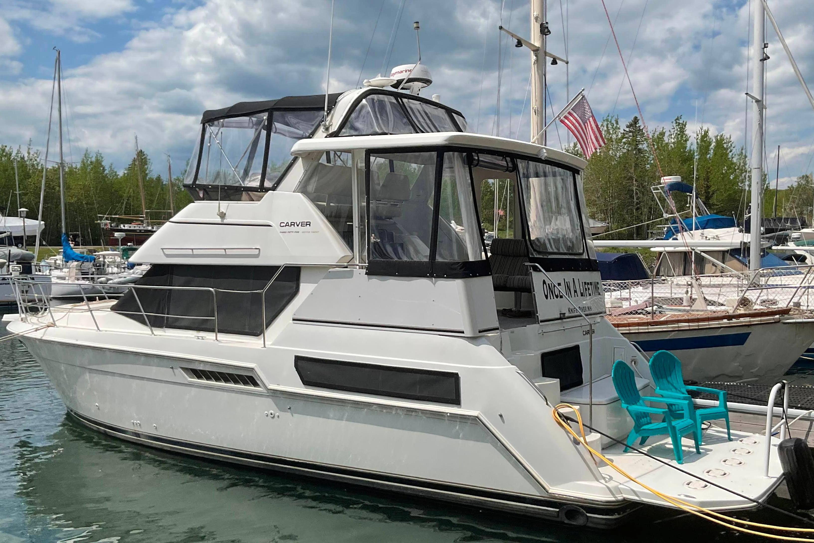 1998 Carver 355 Aft Cabin Motor Yacht docked with blue chairs on deck.