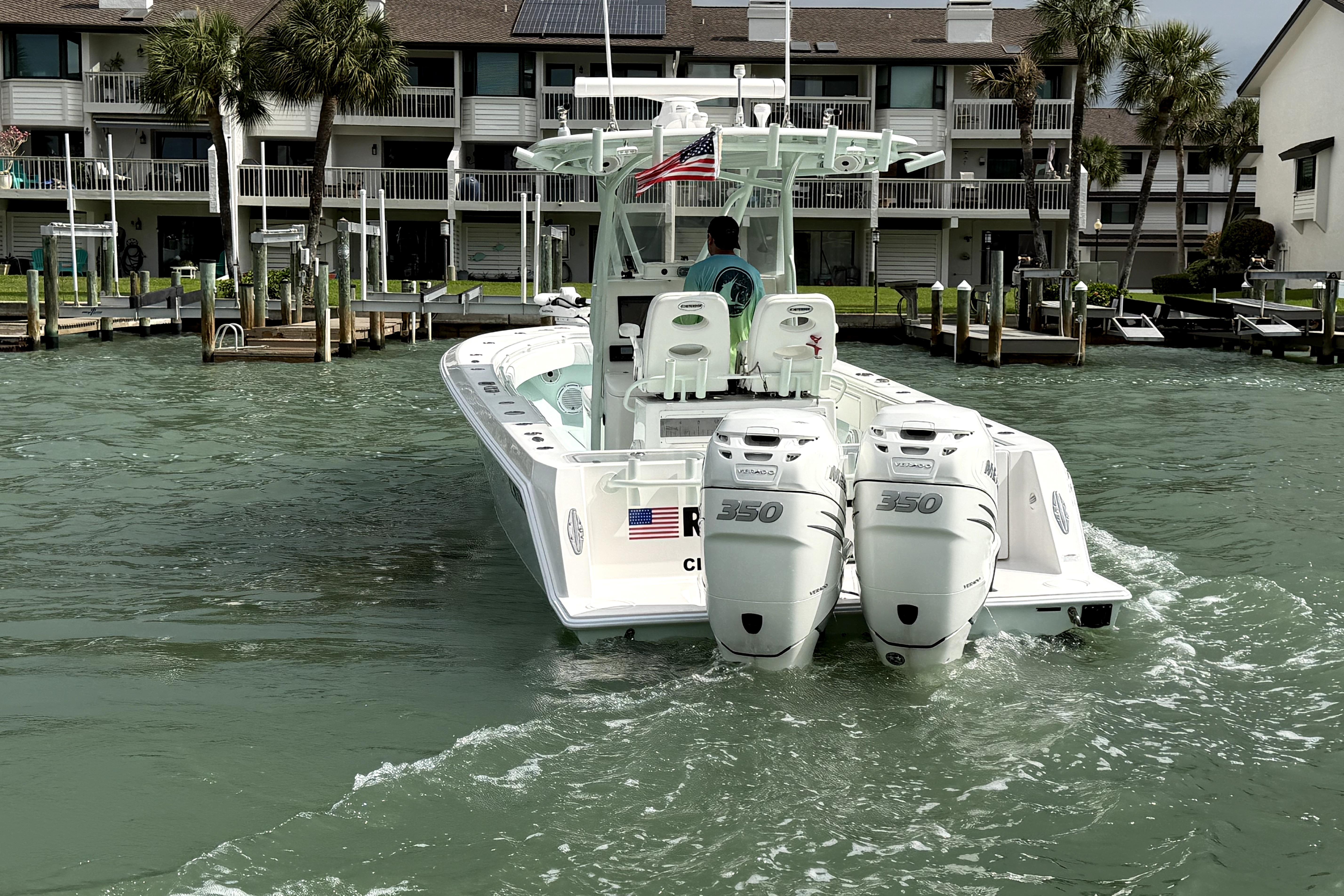 2019 Contender 30 ST boat with twin engines, cruising near waterfront homes.