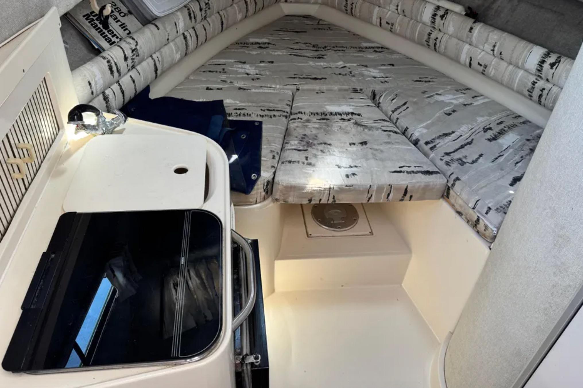 Interior cabin of 1990 Grady-White Marlin 280 boat with cushioned seating and compact kitchenette.