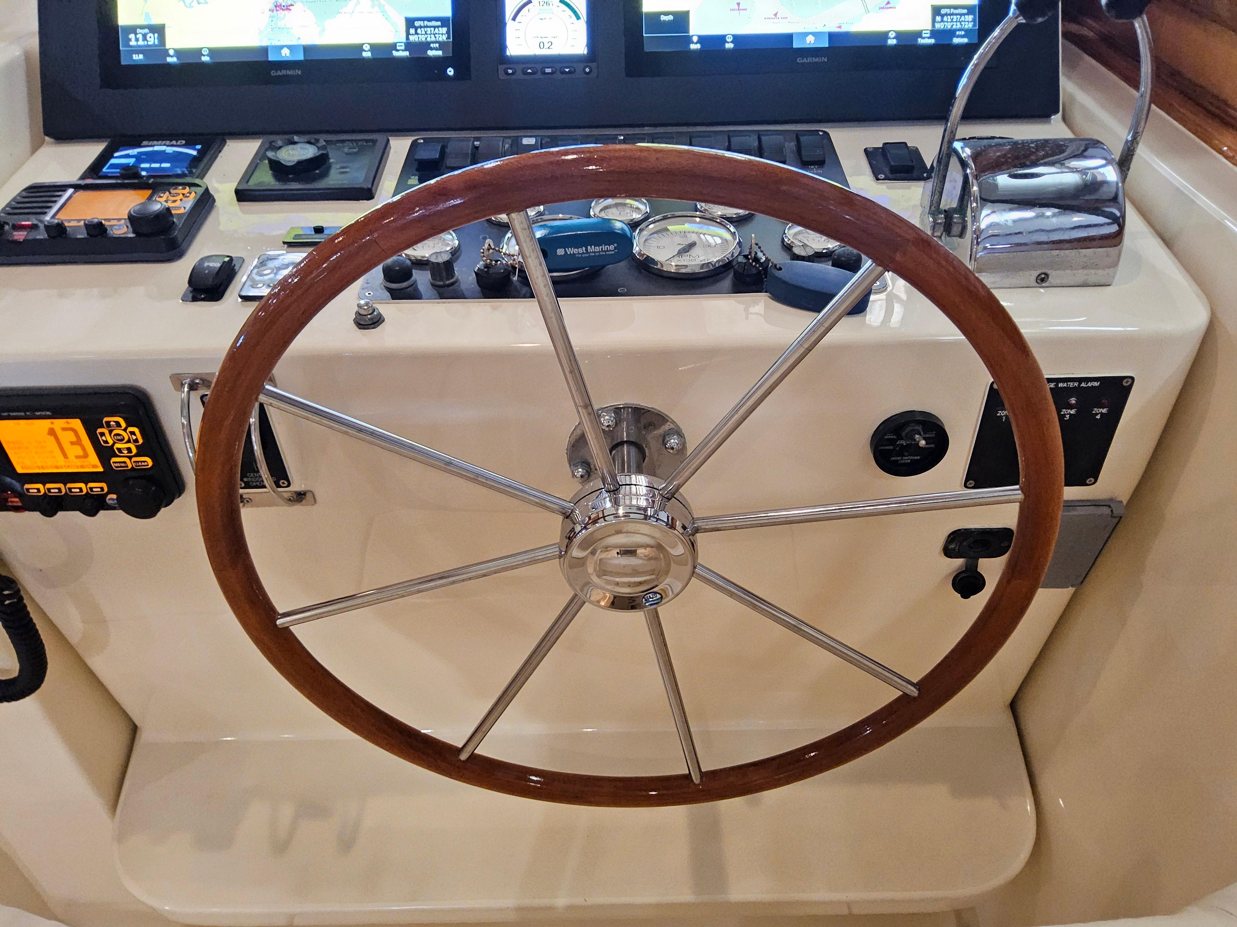 Helm of 2003 Legacy 40 Hardtop Express with wooden steering wheel and navigation instruments.