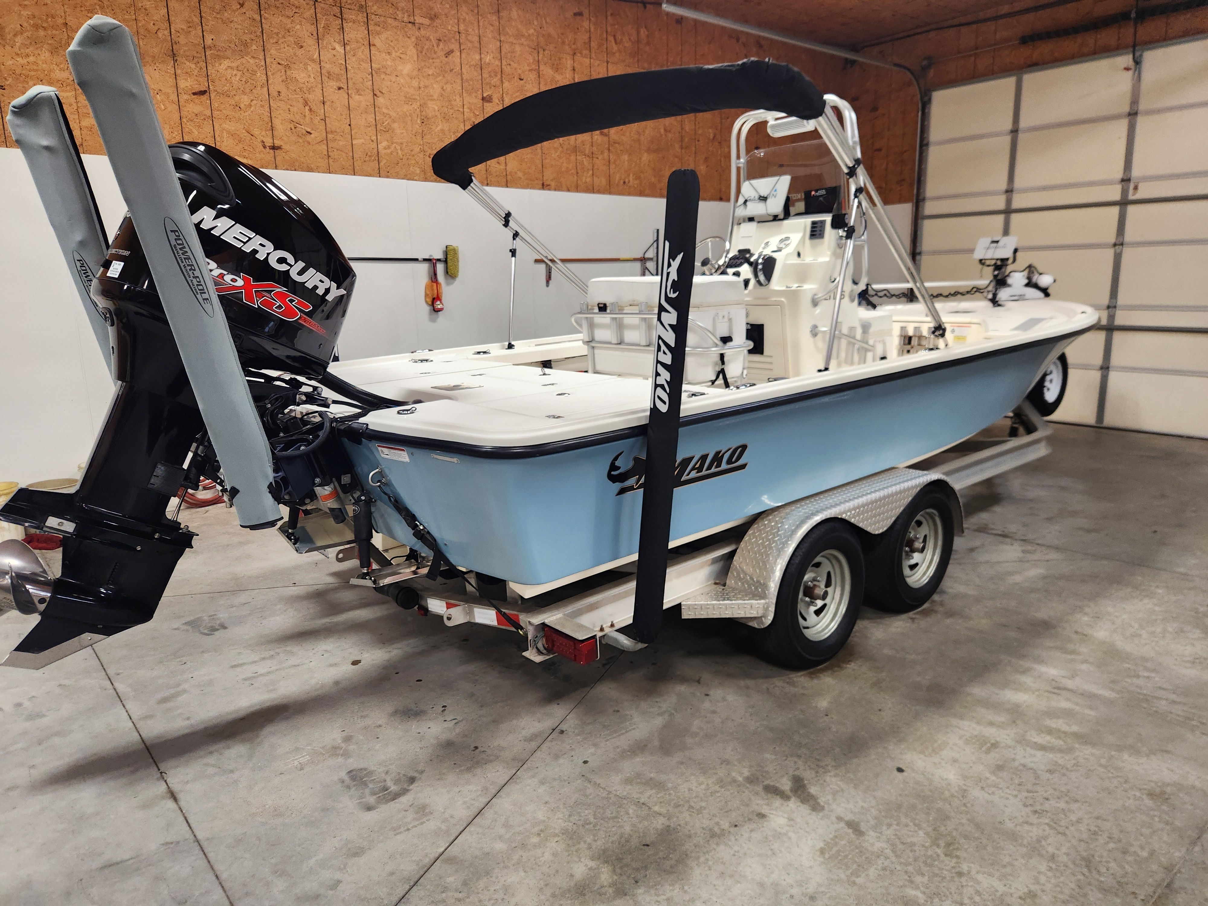 A 2014 Mako 21 LTS boat on a trailer in a garage, featuring a Mercury engine.