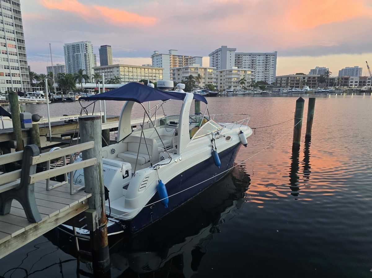 A 2002 Sea Ray Sundancer 260 docked in a city bay, surrounded by buildings.