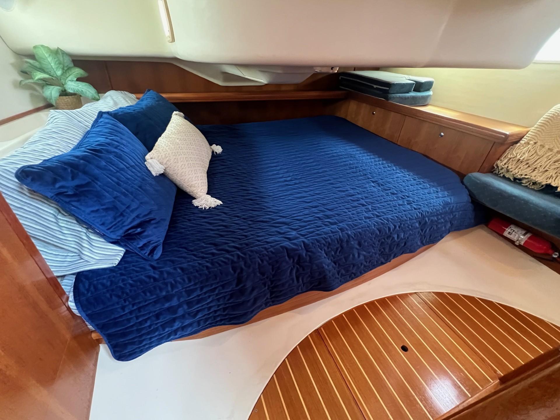 Cozy cabin interior of 2002 Hunter 386 sailboat with blue bedding and wooden accents.