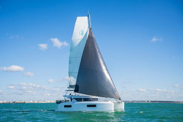 2025 Lagoon 38 catamaran sailing on open water under clear blue skies.