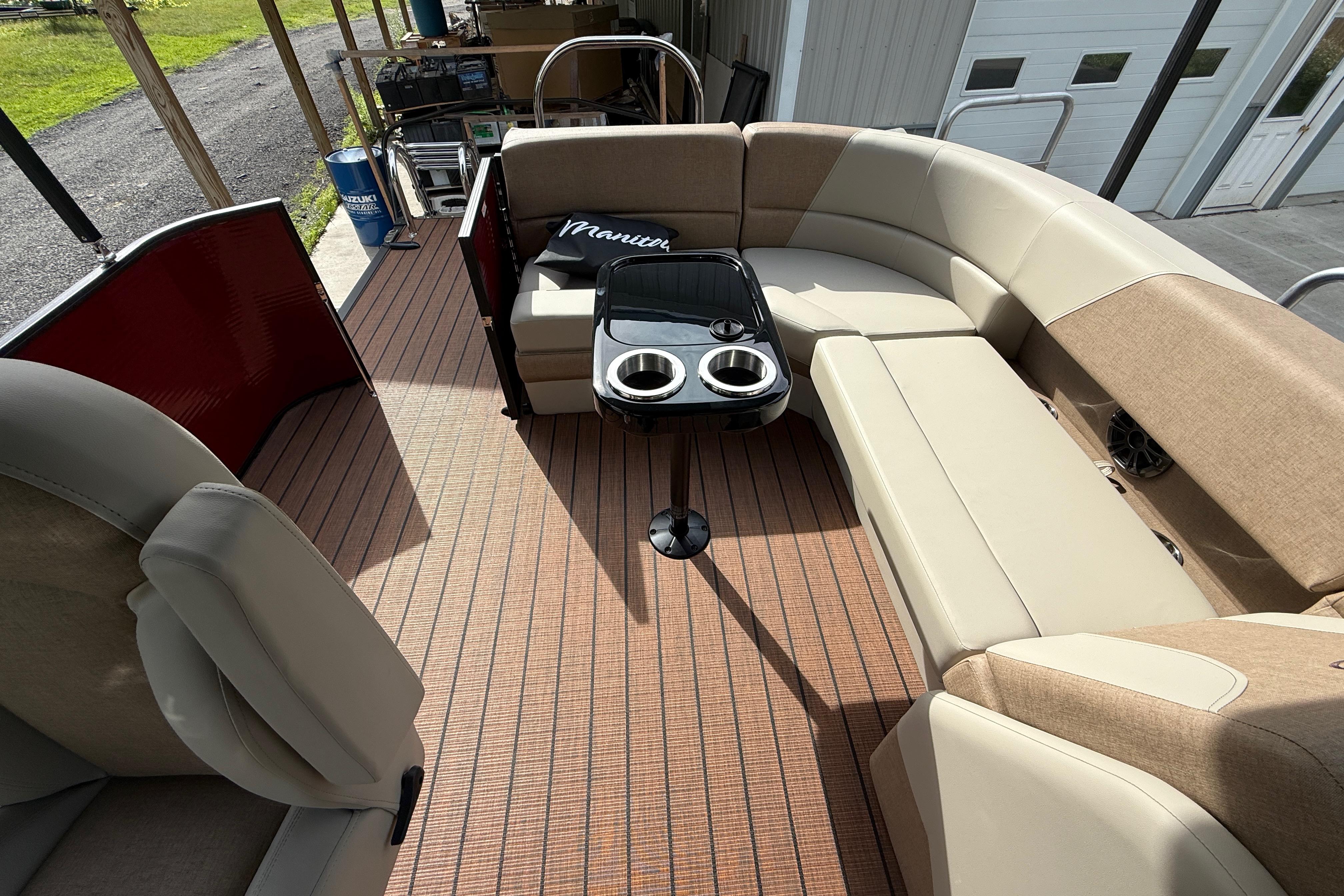 Interior of 2027 Manitou 21 Aurora LE pontoon boat with beige seating and table.