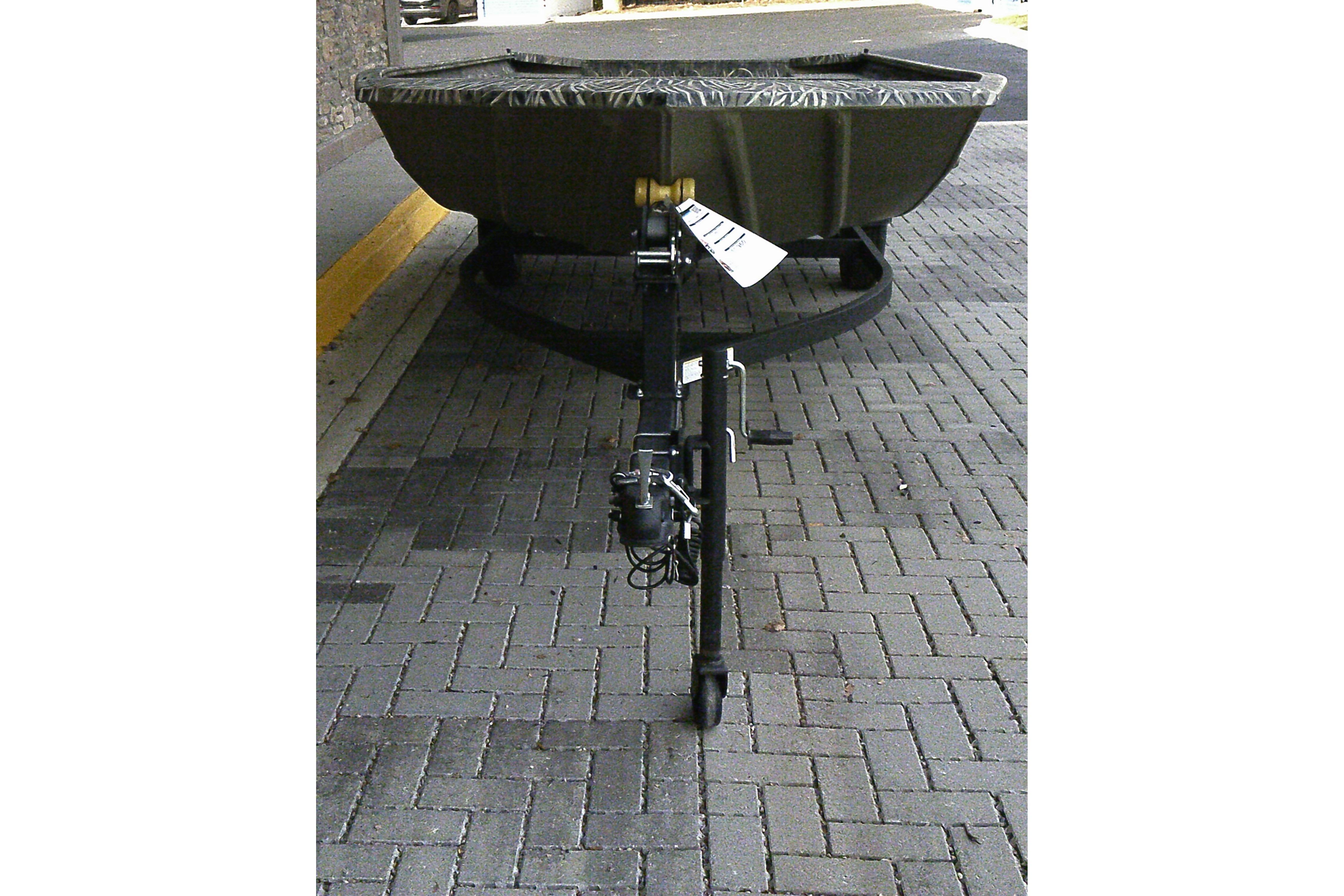 2025 Tracker Grizzly 1860 Utility boat on a trailer, parked on a brick surface.