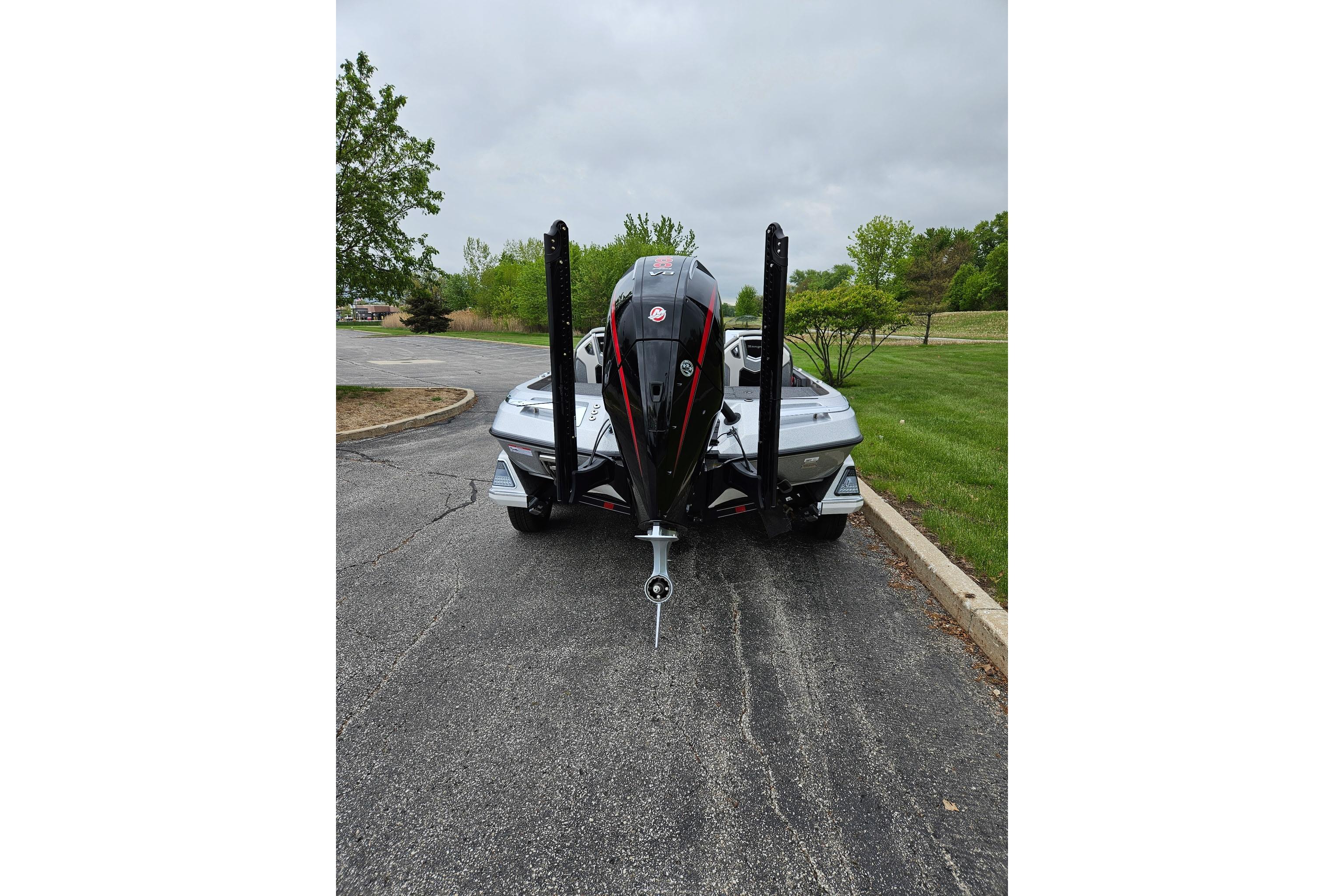 2026 Ranger Z521R Cup-Equipped boat parked on a paved road, surrounded by greenery.