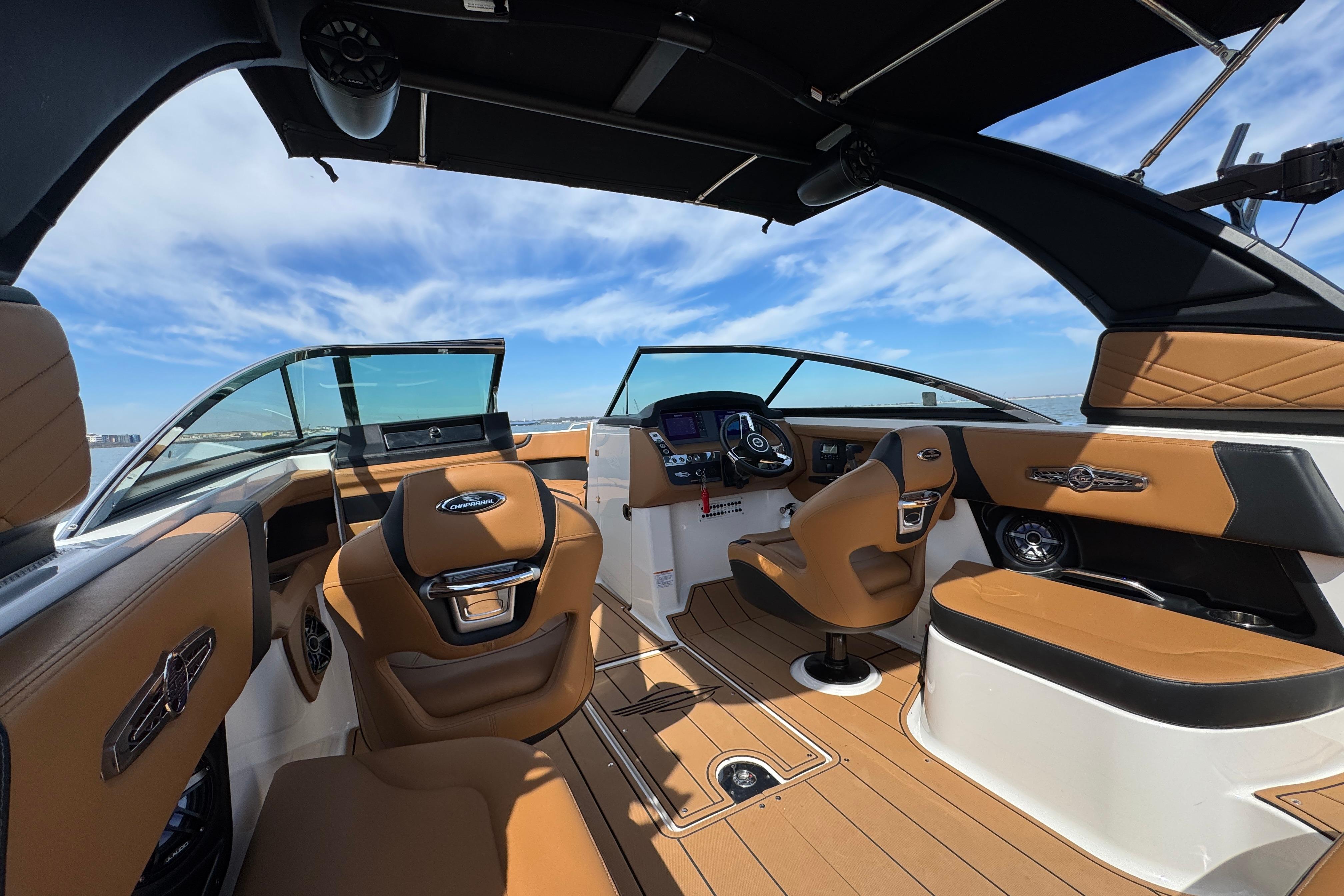 Luxurious interior of 2023 Chaparral 26 Surf boat with tan leather seating and modern dashboard.