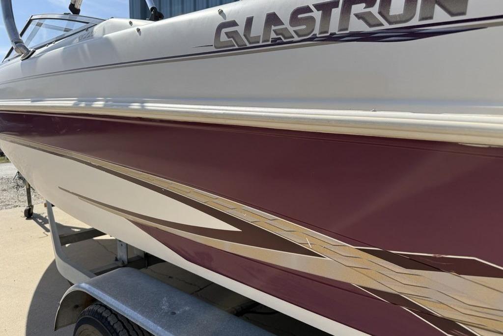 1999 Glastron GT 225 boat with maroon and white detailing on a trailer.