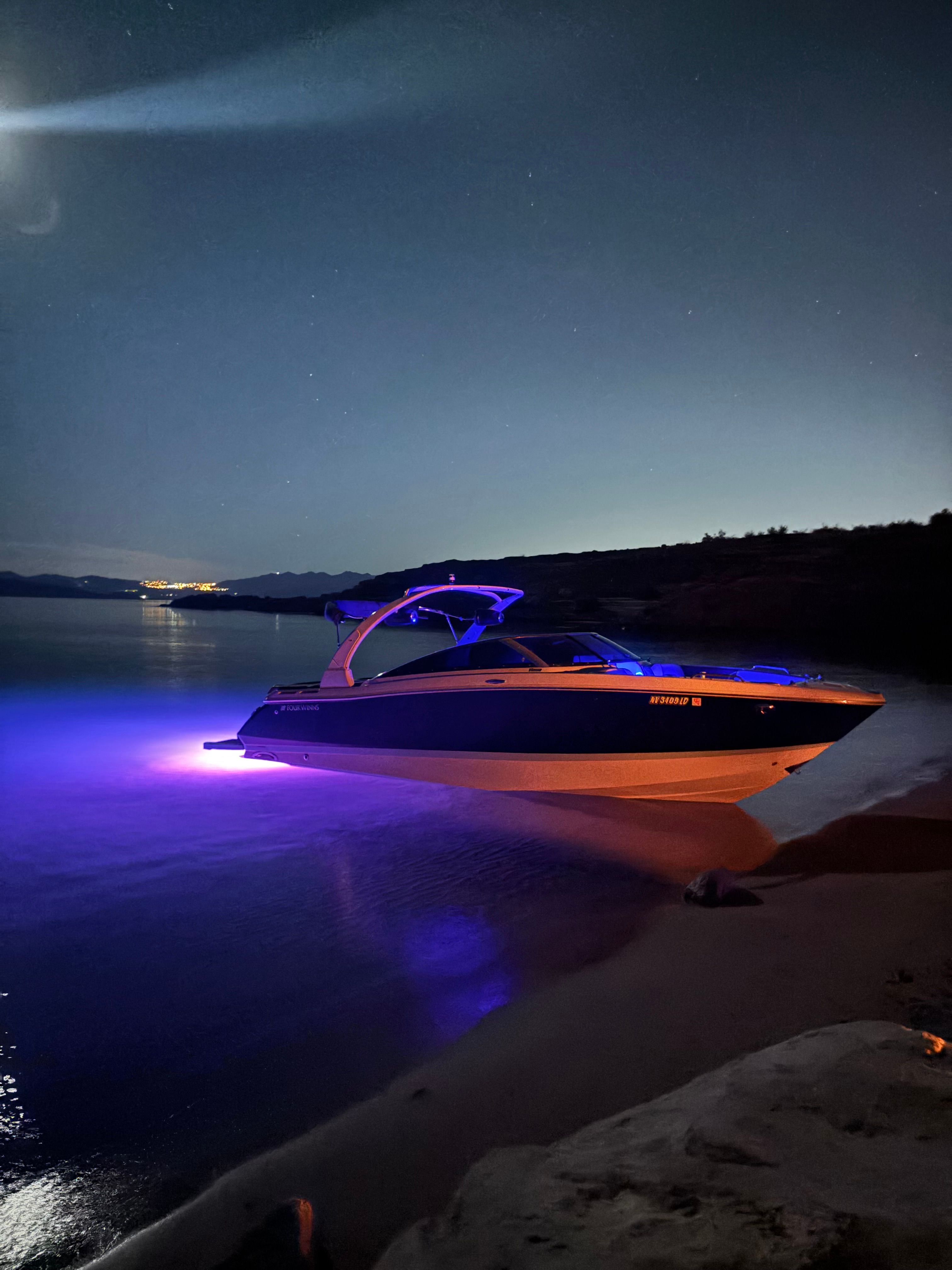 2019 Four Winns H260 boat at night with underwater lighting.