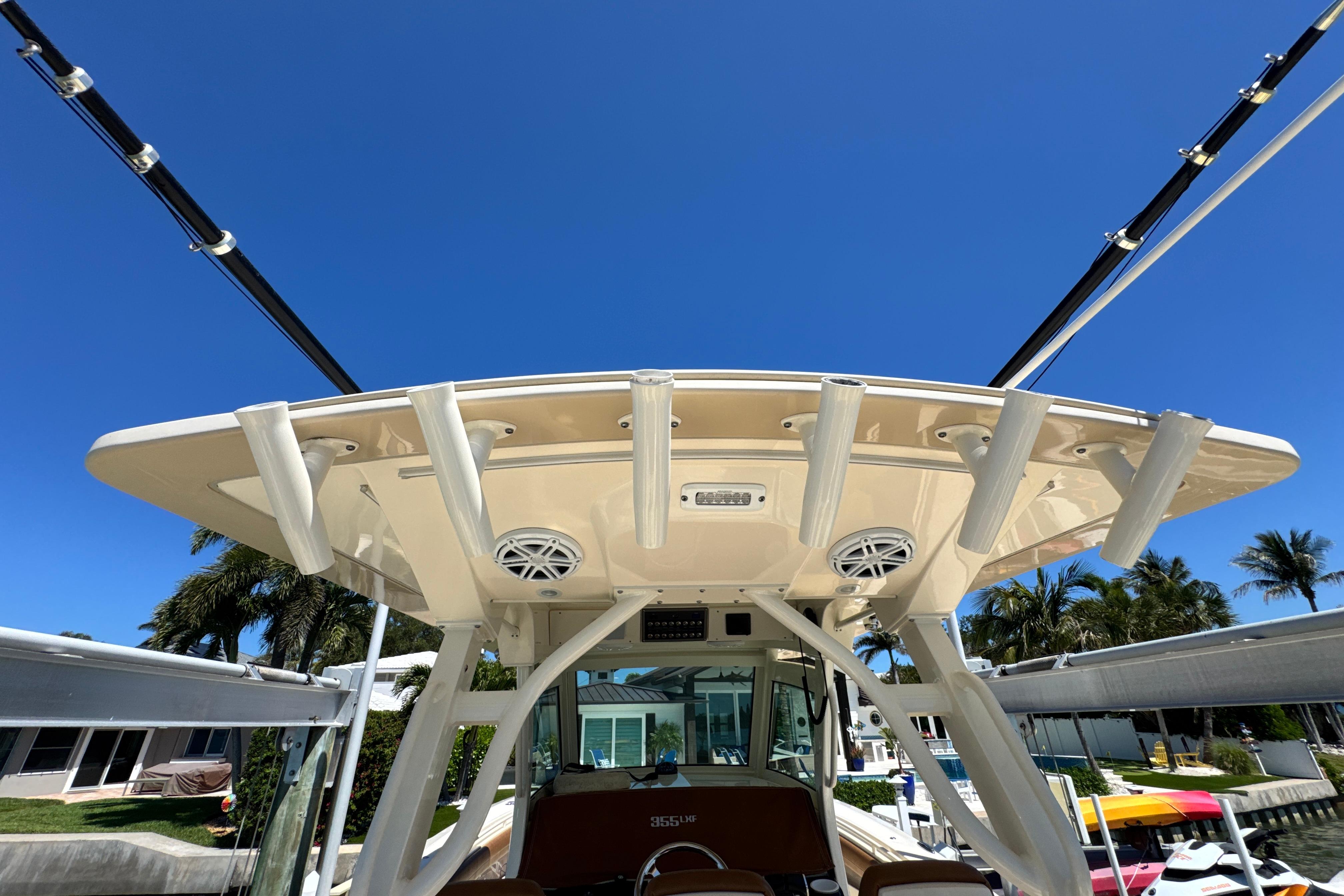 2018 Scout 355 LXF boat with fishing rod holders and speakers under a clear blue sky.