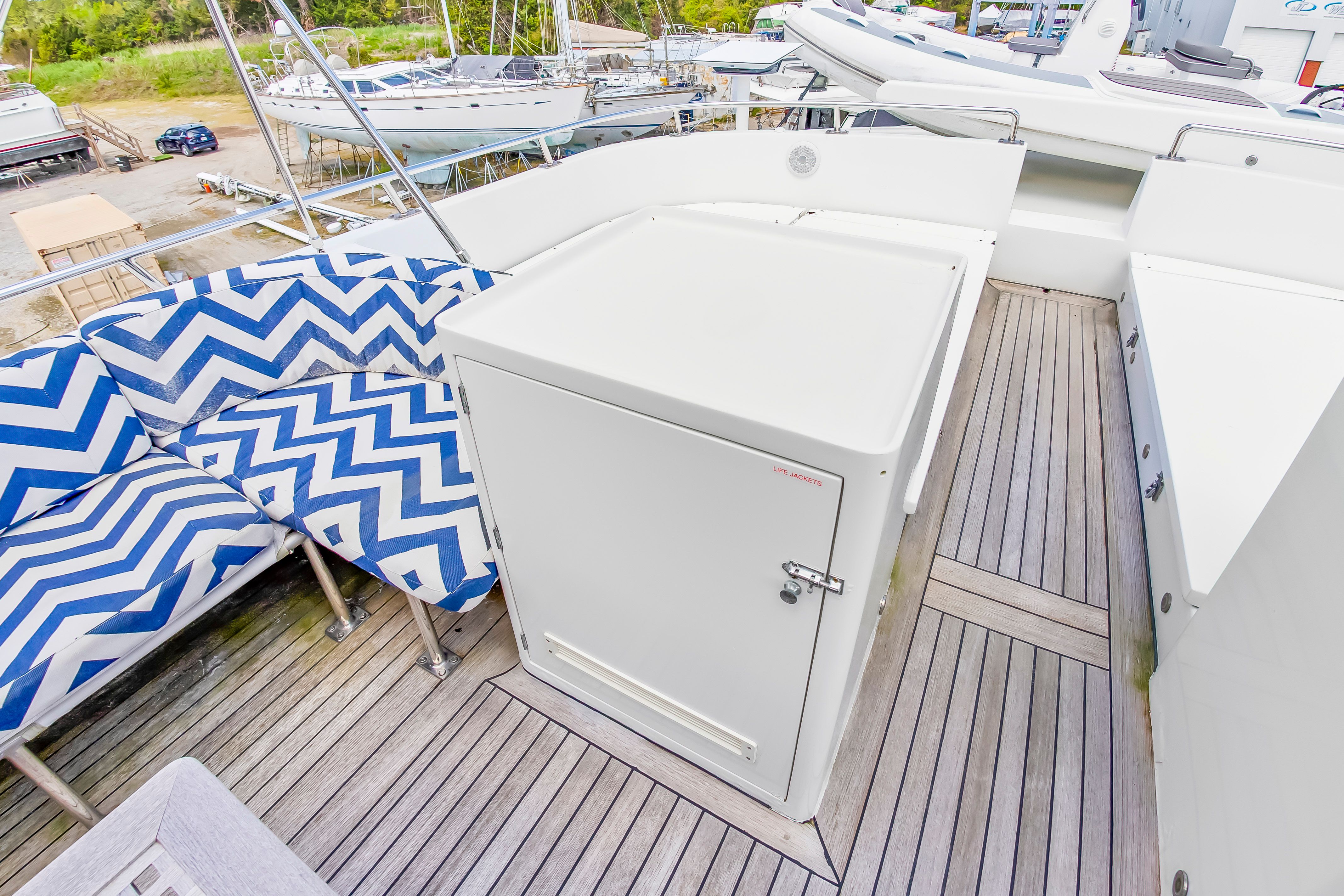 The image shows the deck of a 1987 Jongert 78 Motor Yacht with blue and white patterned cushions.