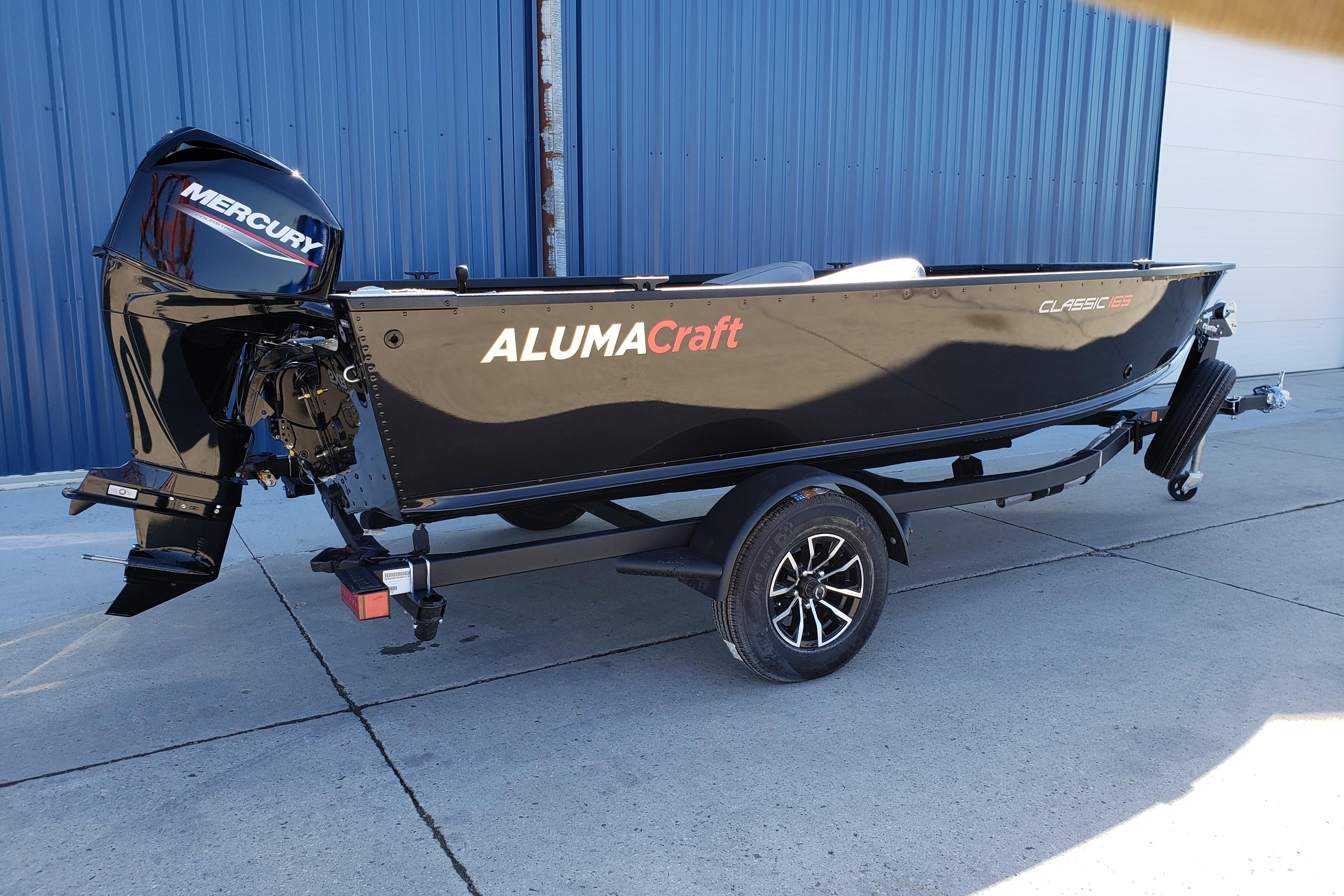 2026 Alumacraft Classic 165 Tiller boat with Mercury engine, parked on a trailer.