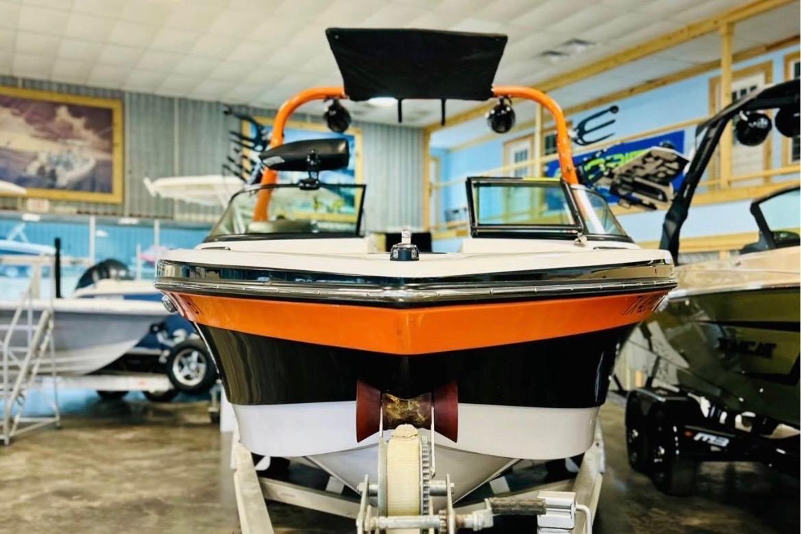 2013 Nautique Super Air Nautique 230 boat in showroom, vibrant orange and black design.