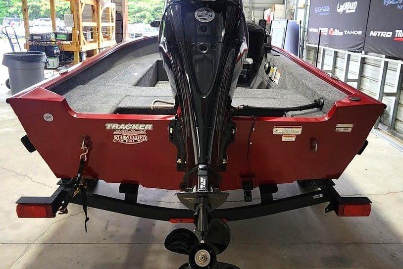 2026 Tracker Super Guide V-16 SC boat with motor, red exterior, in a garage setting.