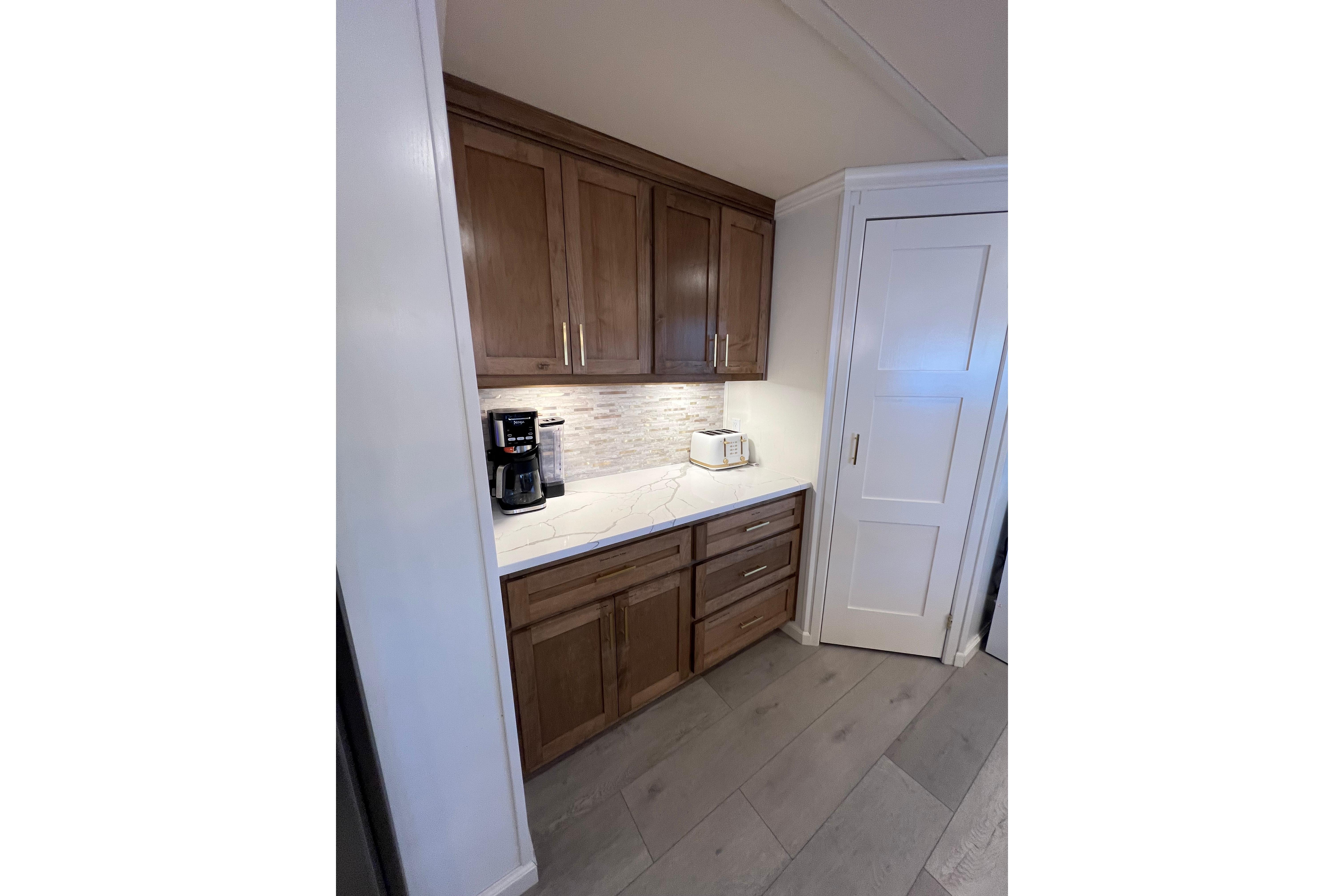 Modern kitchen corner with wooden cabinets, marble countertop, and appliances in a 2025 Sumerset Excellence.