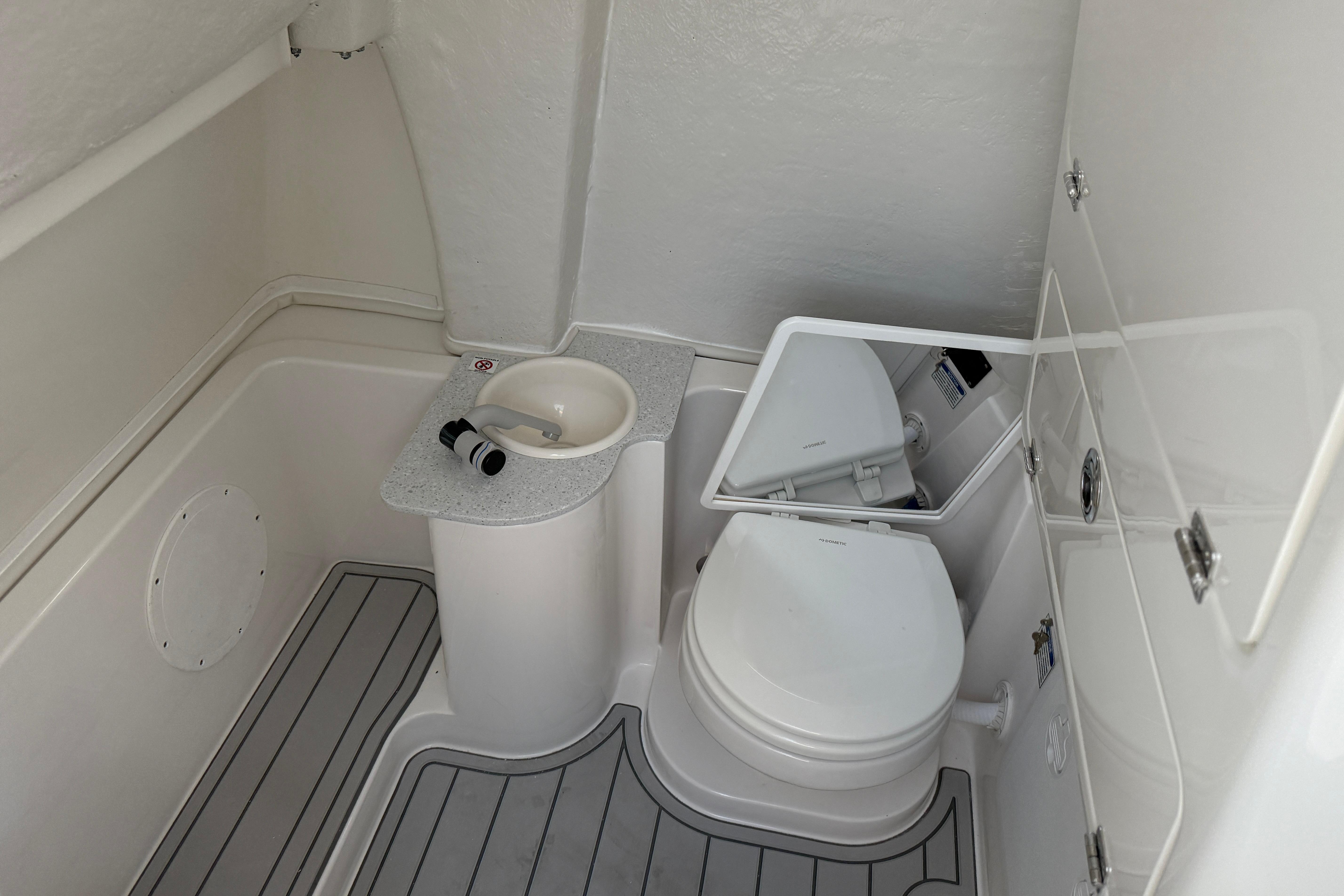 2026 Sea Fox 268 Commander boat bathroom with toilet, sink, and mirror.