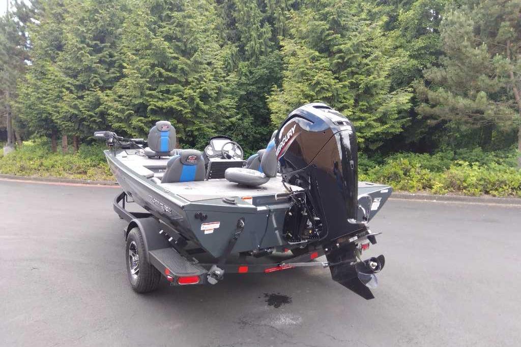 2026 Ranger RT178 boat with Mercury engine, parked on a trailer near lush greenery.