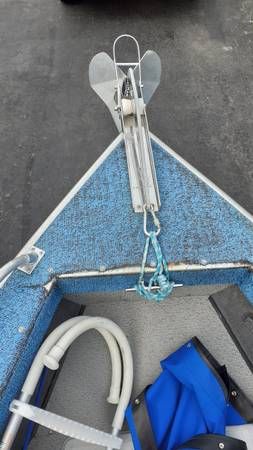 A boat with blue carpeting and an anchor at the bow.
