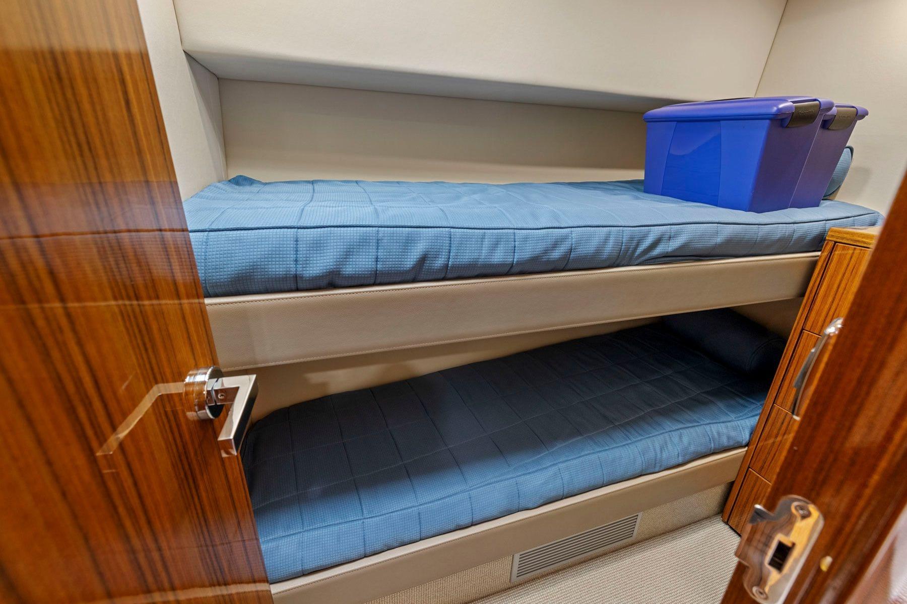 Bunk beds in 2014 Maritimo M50 yacht cabin with blue bedding and storage box.