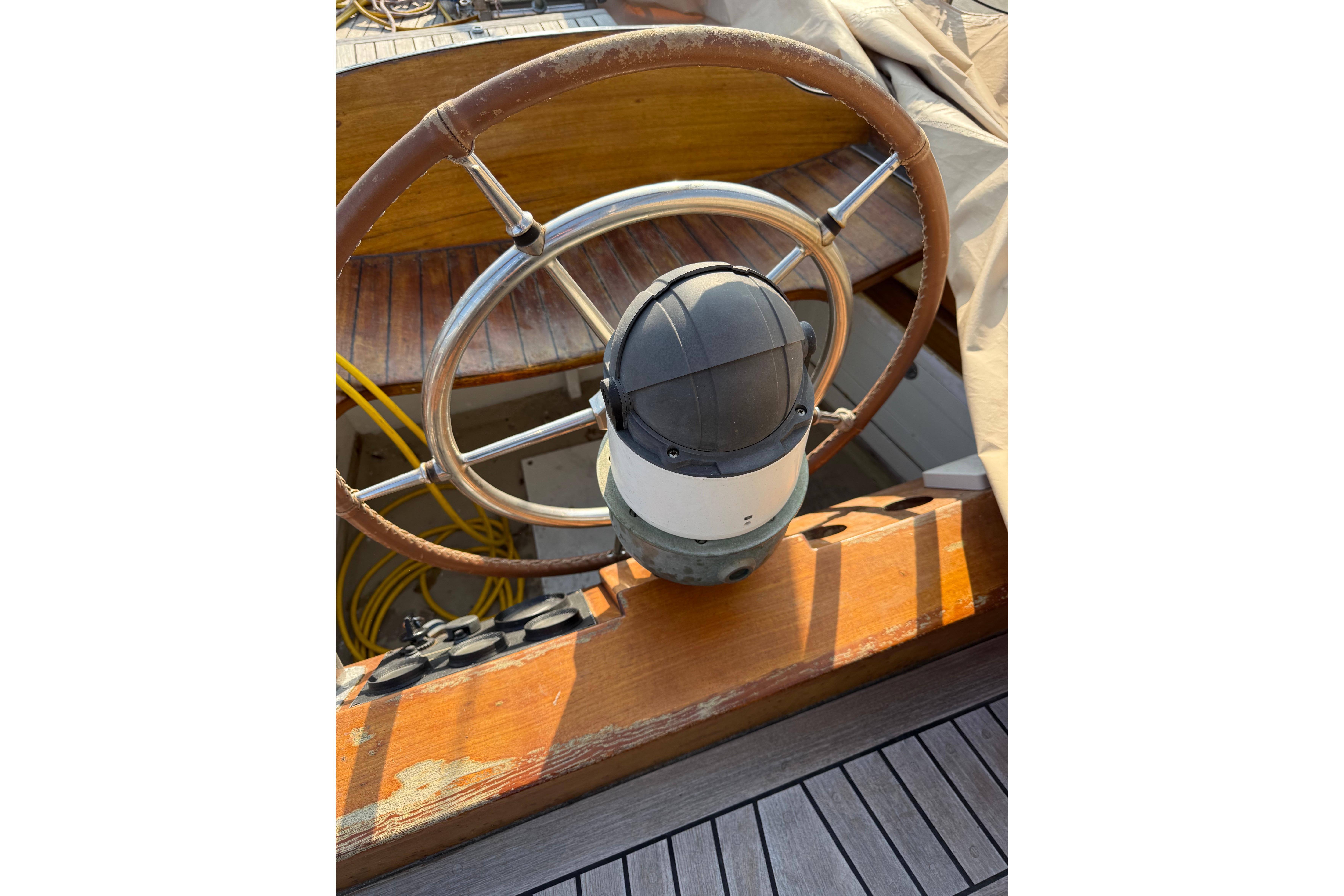 1958 Costantini Ketch Marconi steering wheel and compass on wooden deck.