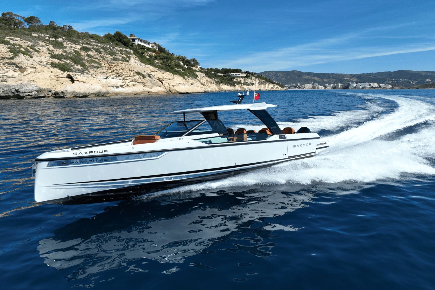A 2027 Saxdor SX320 GTO speeds across blue water near a rocky coastline.