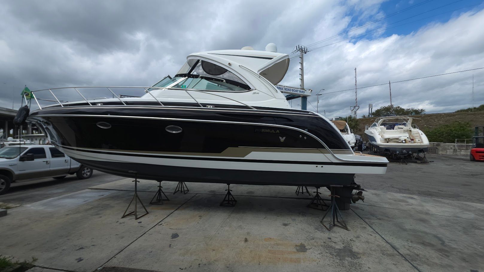 A black and white motor yacht is on a dry dock under a cloudy sky.