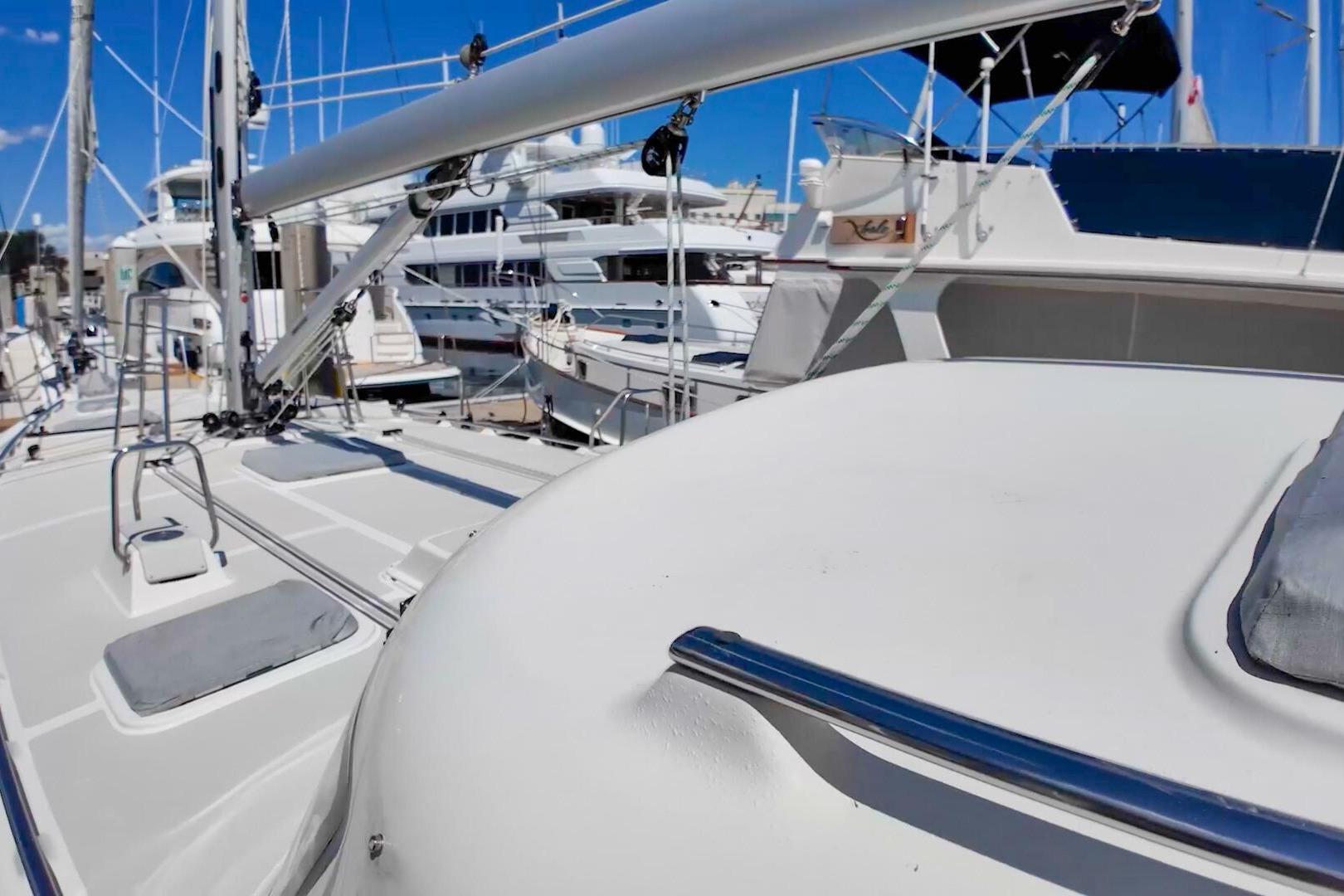 2023 Island Packet 439 sailboat deck with marina background, showcasing sleek design and modern features.