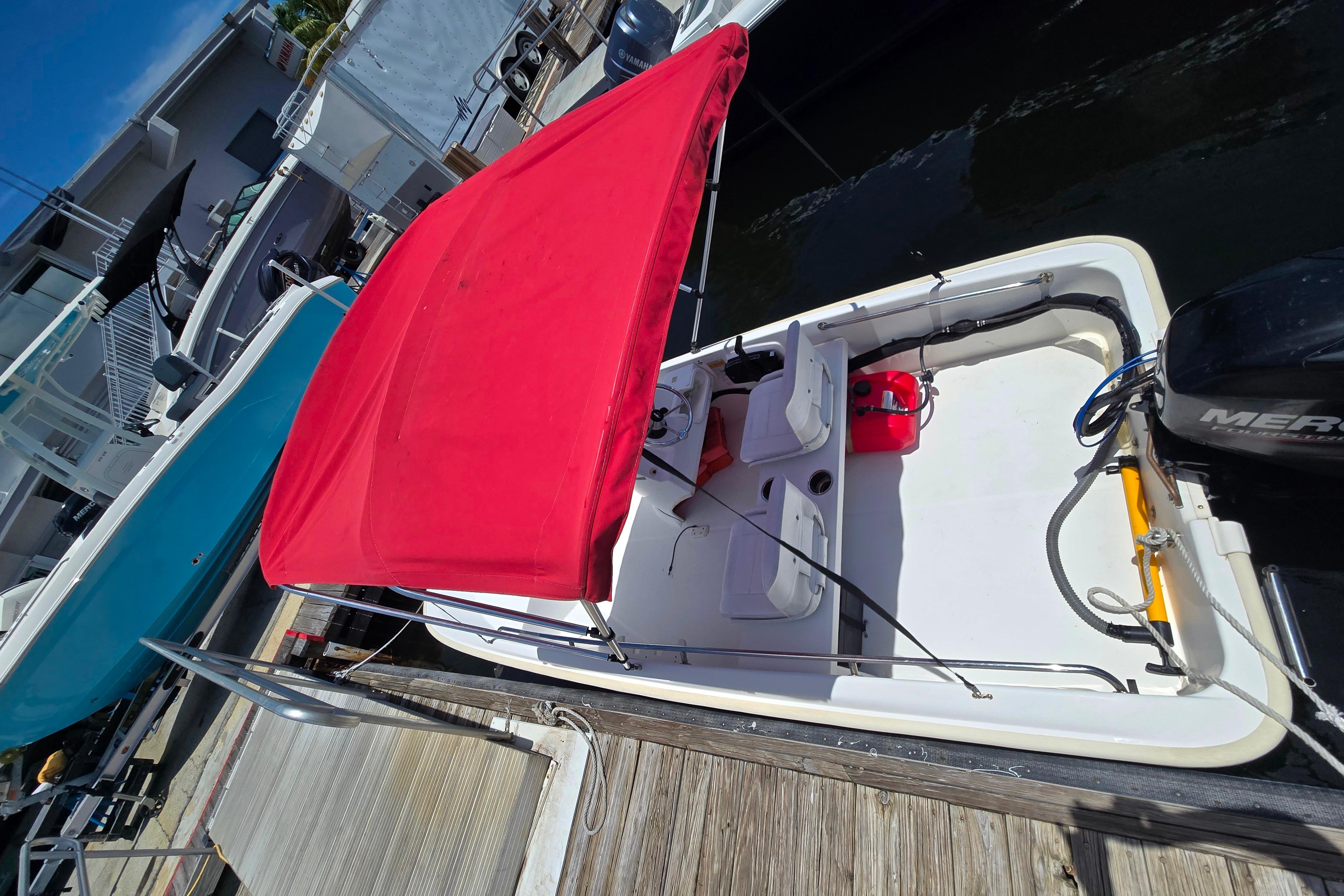 2014 Boston Whaler 13 SS boat with red canopy docked at marina.